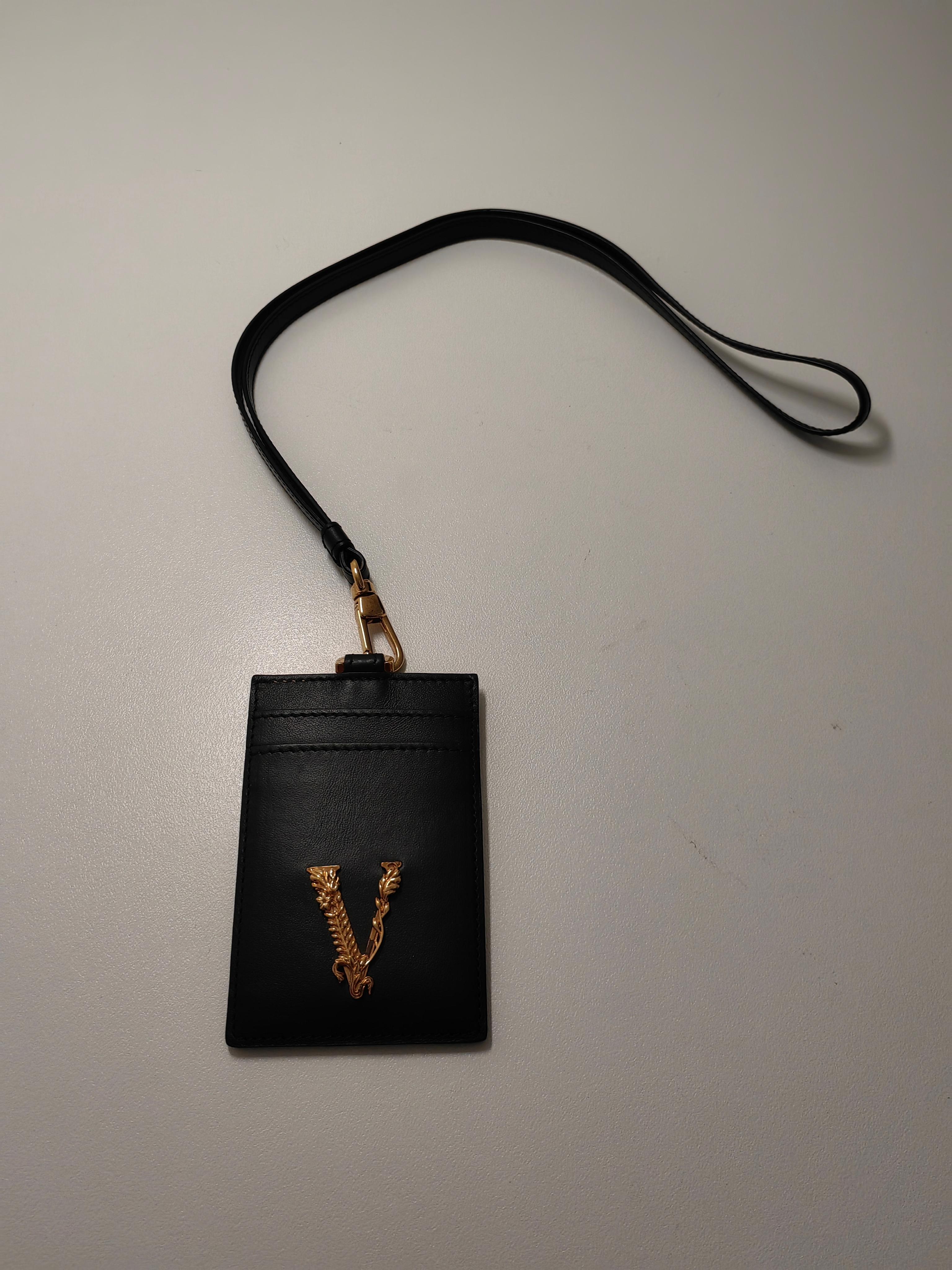 Add a touch of luxury to your everyday essentials with the Versace Virtus Lanyard ID Card Holder in black. Designed to combine practicality and elegance, this sleek accessory is part of the renowned Virtus collection, renowned for its bold 'V'