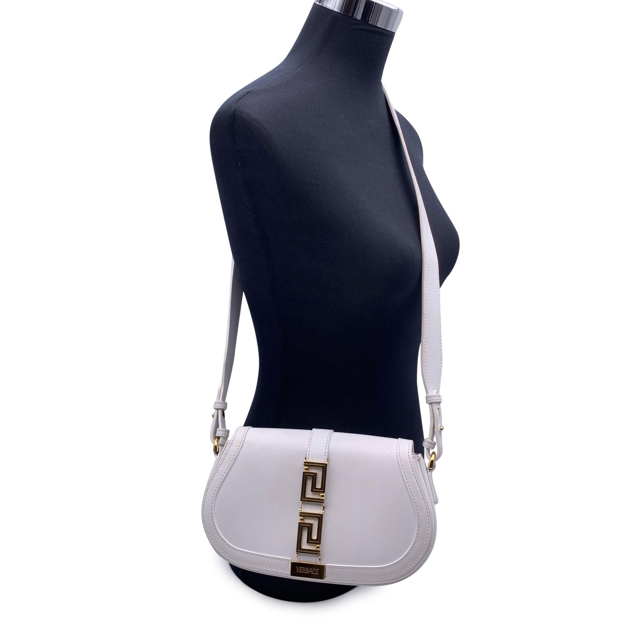 Versace 'Greca Goddess' shoulder bag in white calf leather. It features a gold metal central Greca on the front. Adjustable leather shoulder strap. Magnetic button closure. White leather lining. 1 open pocket inside. 'Versace - Made in Italy'