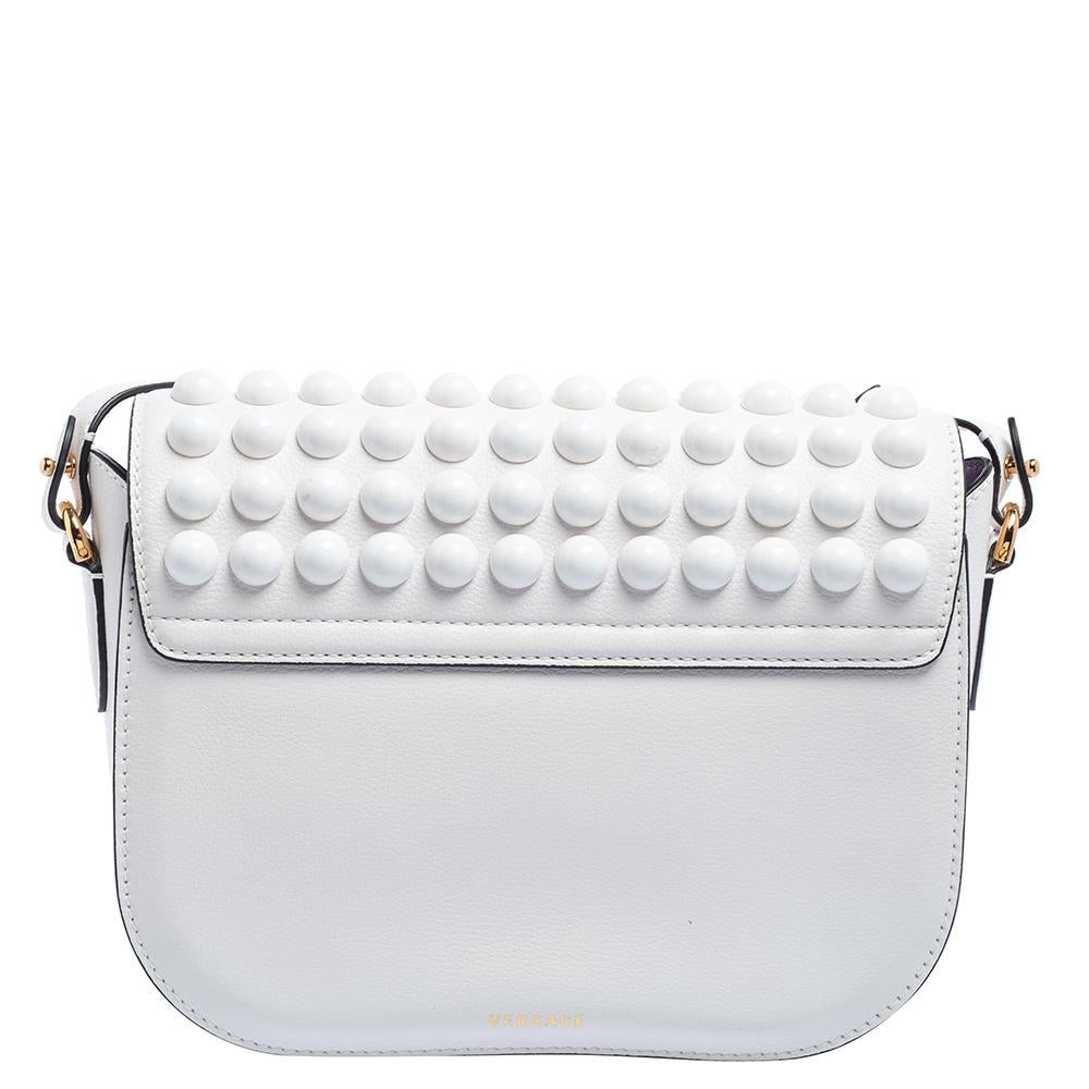 The house of Versace is known for its sleek designs, just like this white shoulder bag that has been crafted from leather. It has gold-tone hardware and comes with a Medusa head on the stylish front flap that opens into a spacious interior. Take it