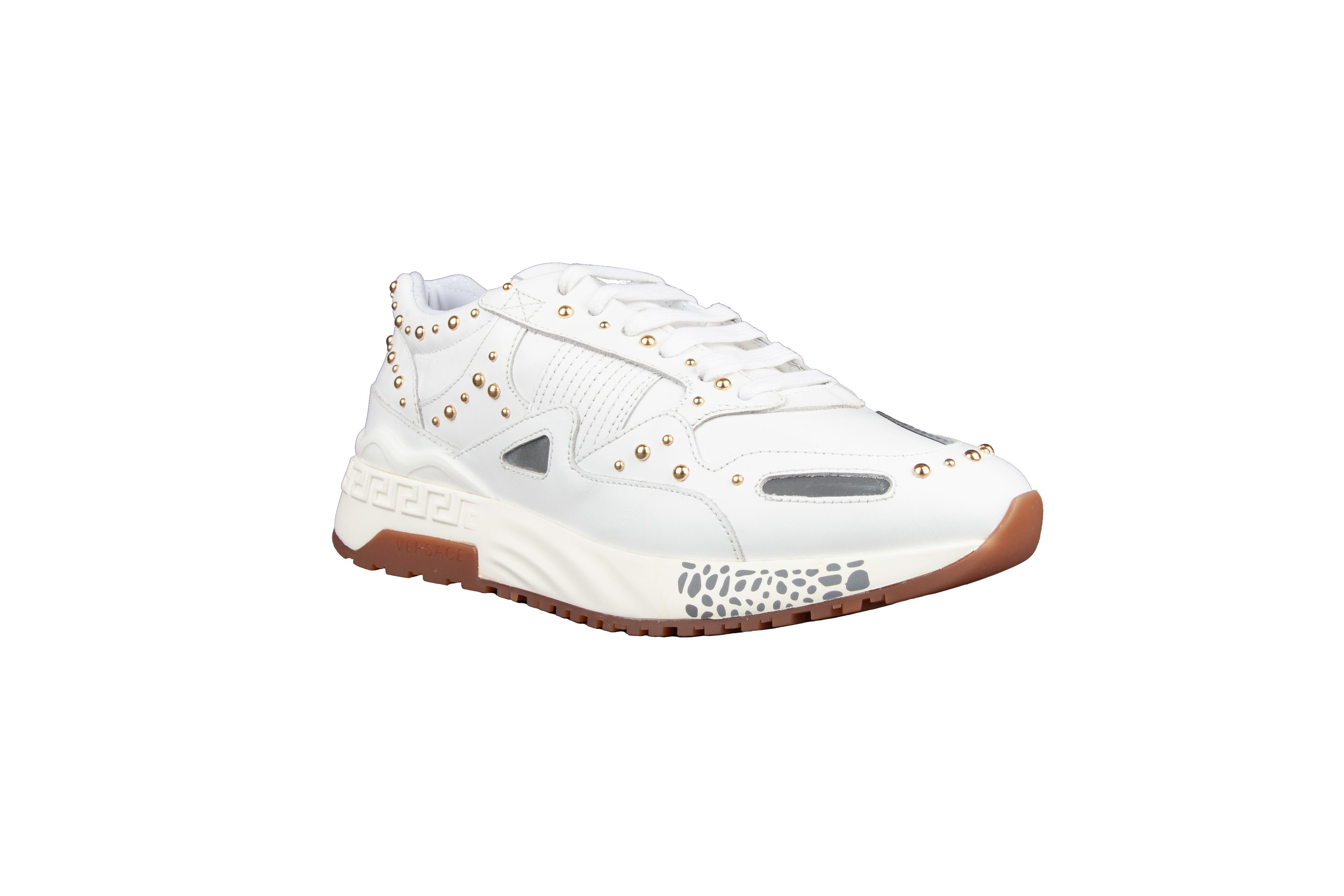 These Versace leather sneakers feature gold tone studs, a lace-up front closure and greca key detailing along the rubble sole. A classic white sneaker with added flare. Brand new. Made in Italy.

Size : 36.5 (IT)