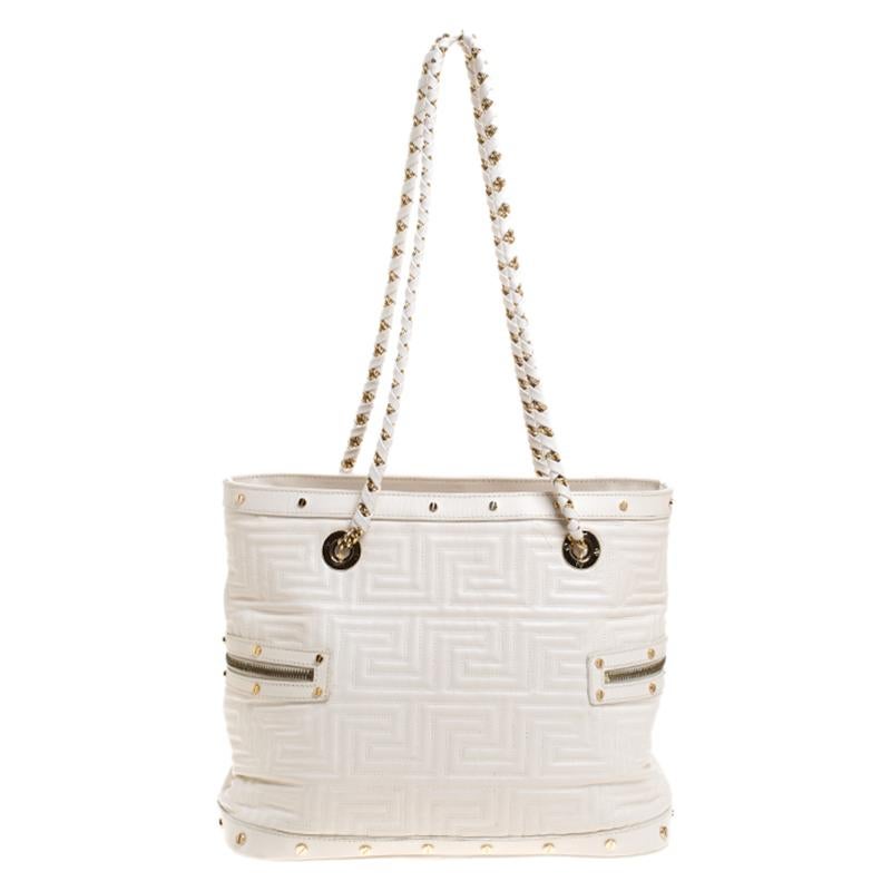 Crafted to perfection, this white Versace tote is crafted from quilted leather. It features top handles, gold-tone hardware, zipper detailing on both the sides and a metal logo plaque on the front. The tote opens to a satin-lined interior housing