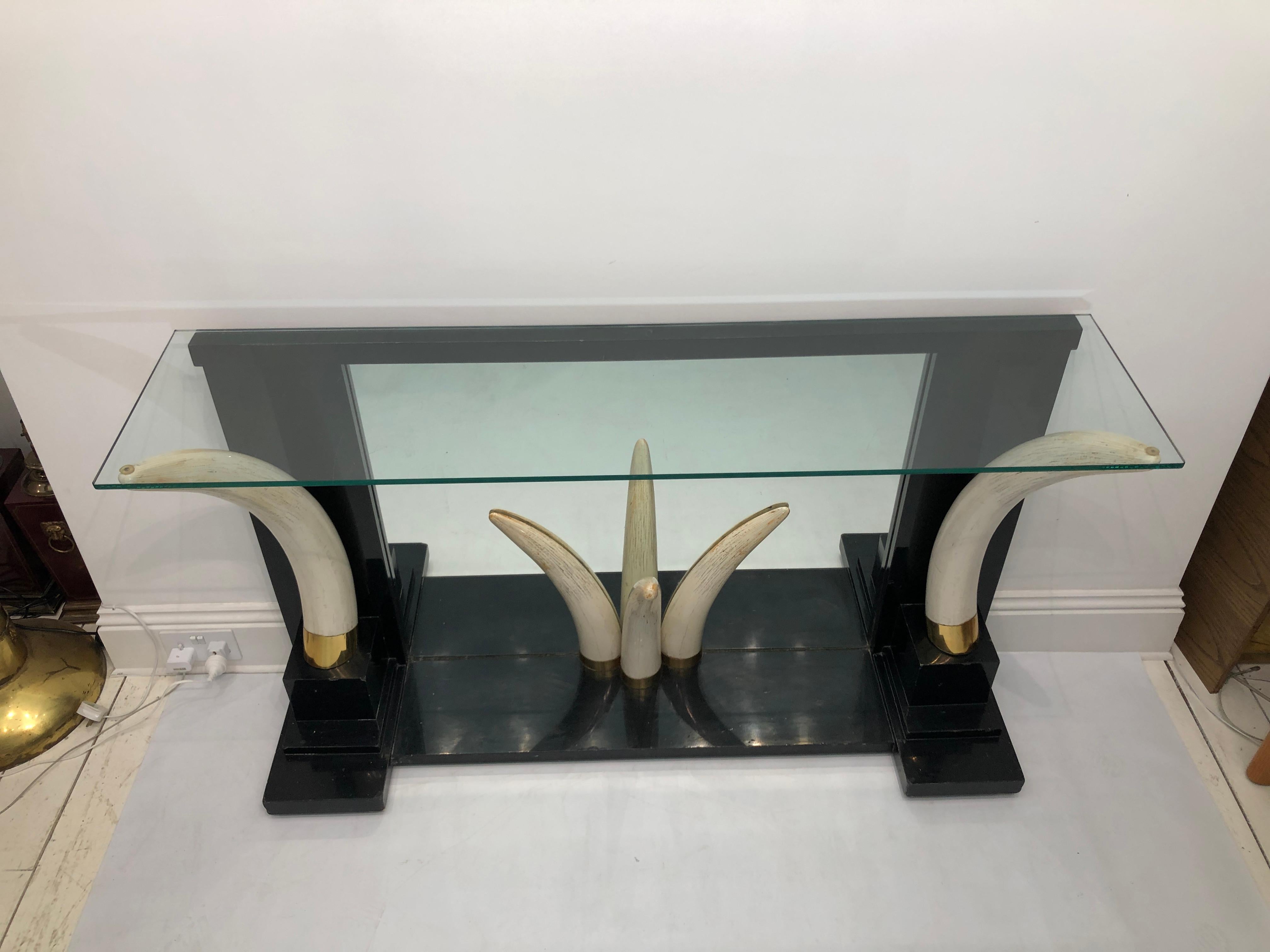 An exceptional and striking console table by the Versailles Collection possibly designed by Suzanne Dahl and Jerry Barich.

A pair of large faux elephant tusks in brass fitting stand atop an ebony pedestal base and flank a small trio a faux tusks