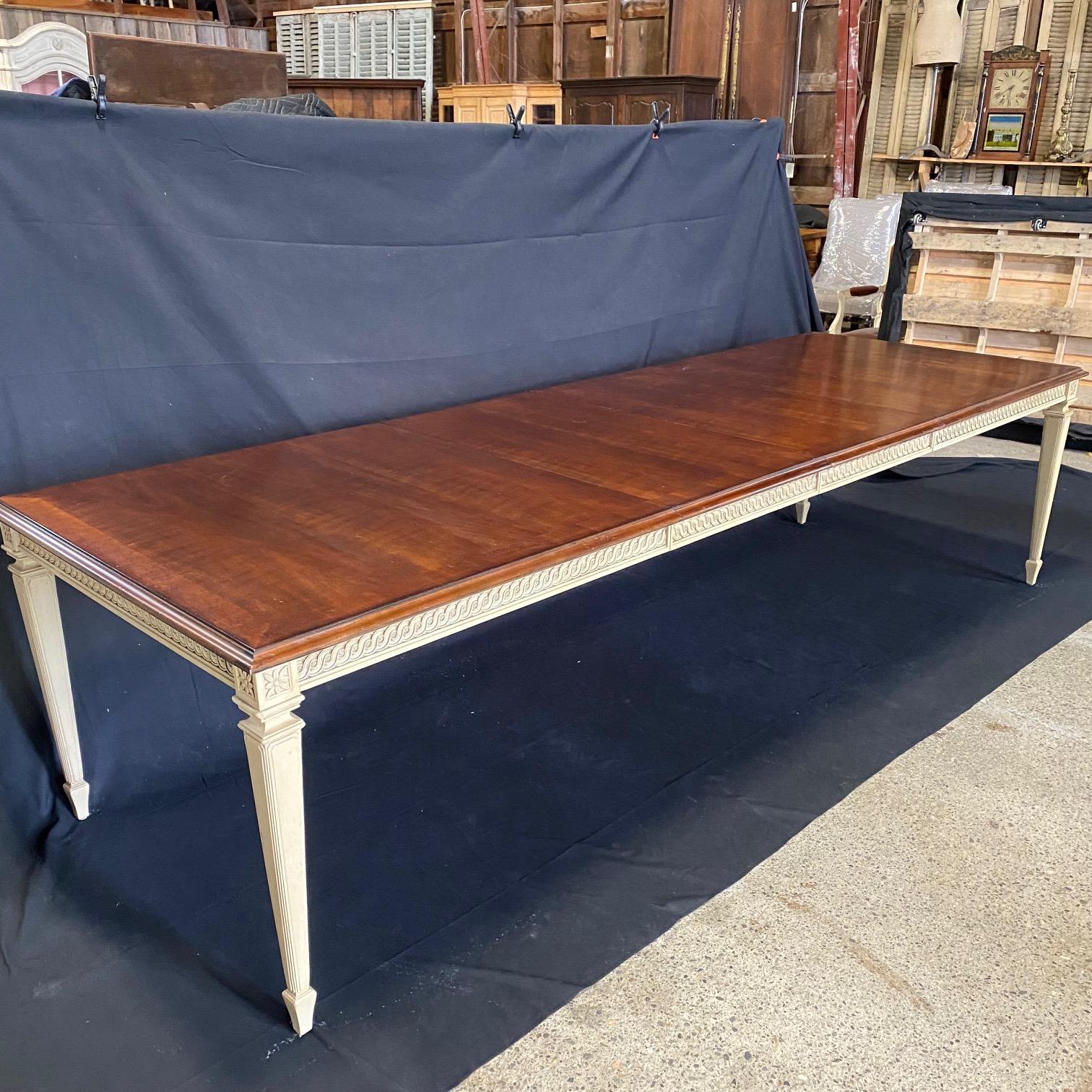French neoclassical style dining table with carved side details over tapered legs, and lovely richly stained walnut top with banded edge all around. Two large leaves; this lovely table can extend from 6 and a half feet (seating up to 8 people) to