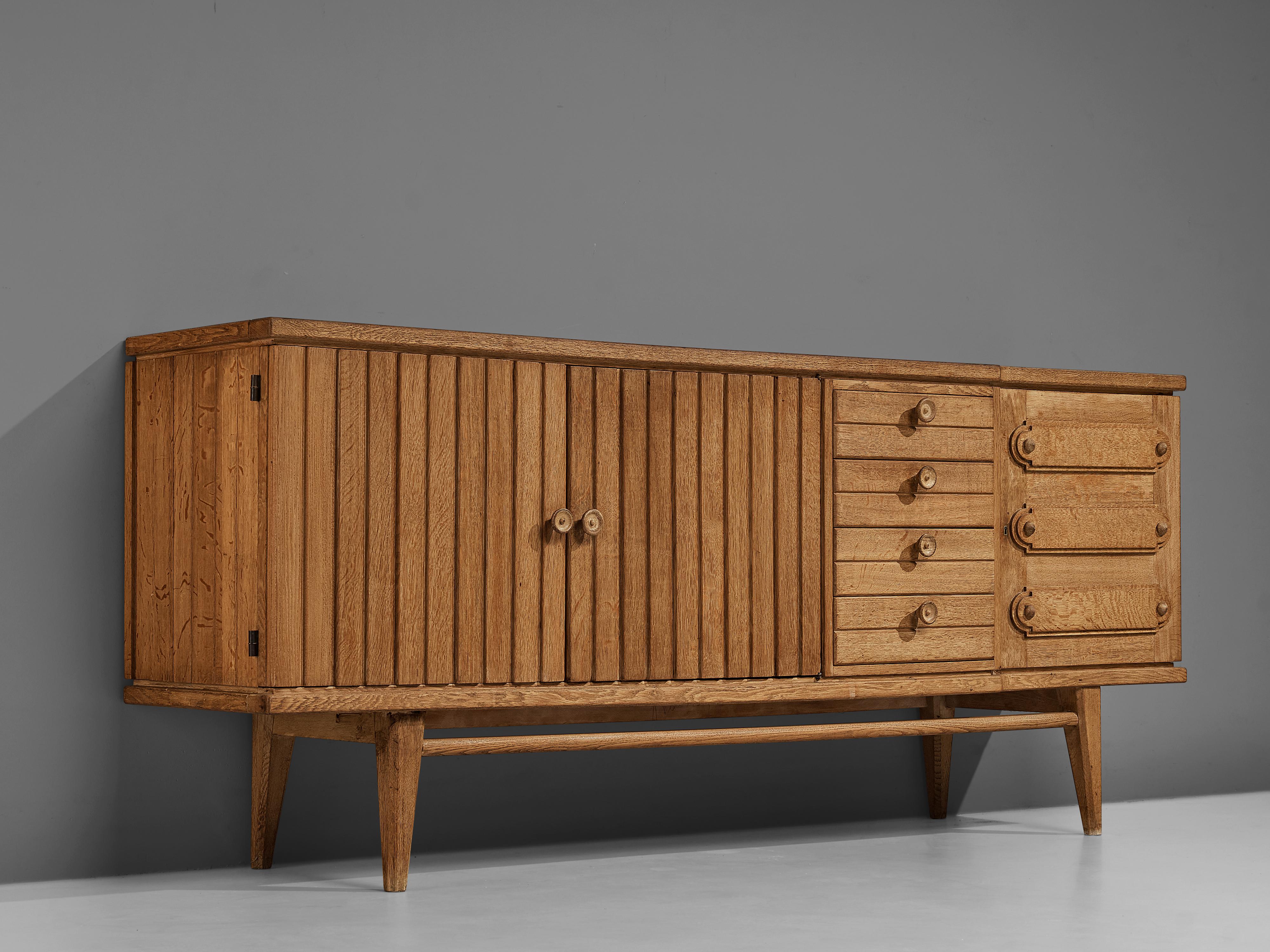 French sideboard, oak, France, 1960s

With the vividly designed fronts and the functional and versatile storage facilities this high-quality sideboard serves both visual and practical aspects. A section of drawers is flanked by one door with