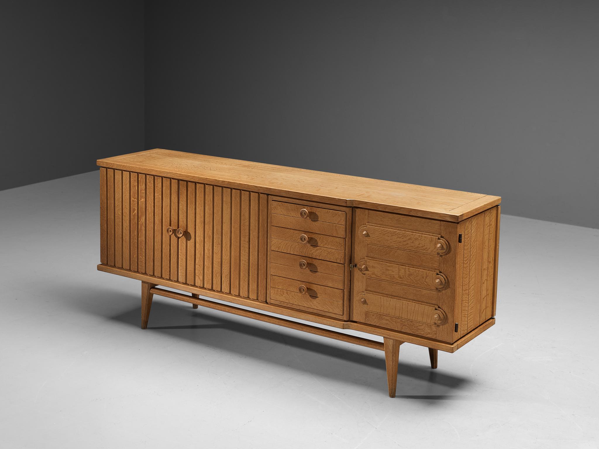 Sideboard, oak, brass, France, 1960s

French sideboard made in oak with beautiful grain and detailing. With the vividly designed fronts and the functional and versatile storage facilities this high-quality sideboard serves both visual and practical