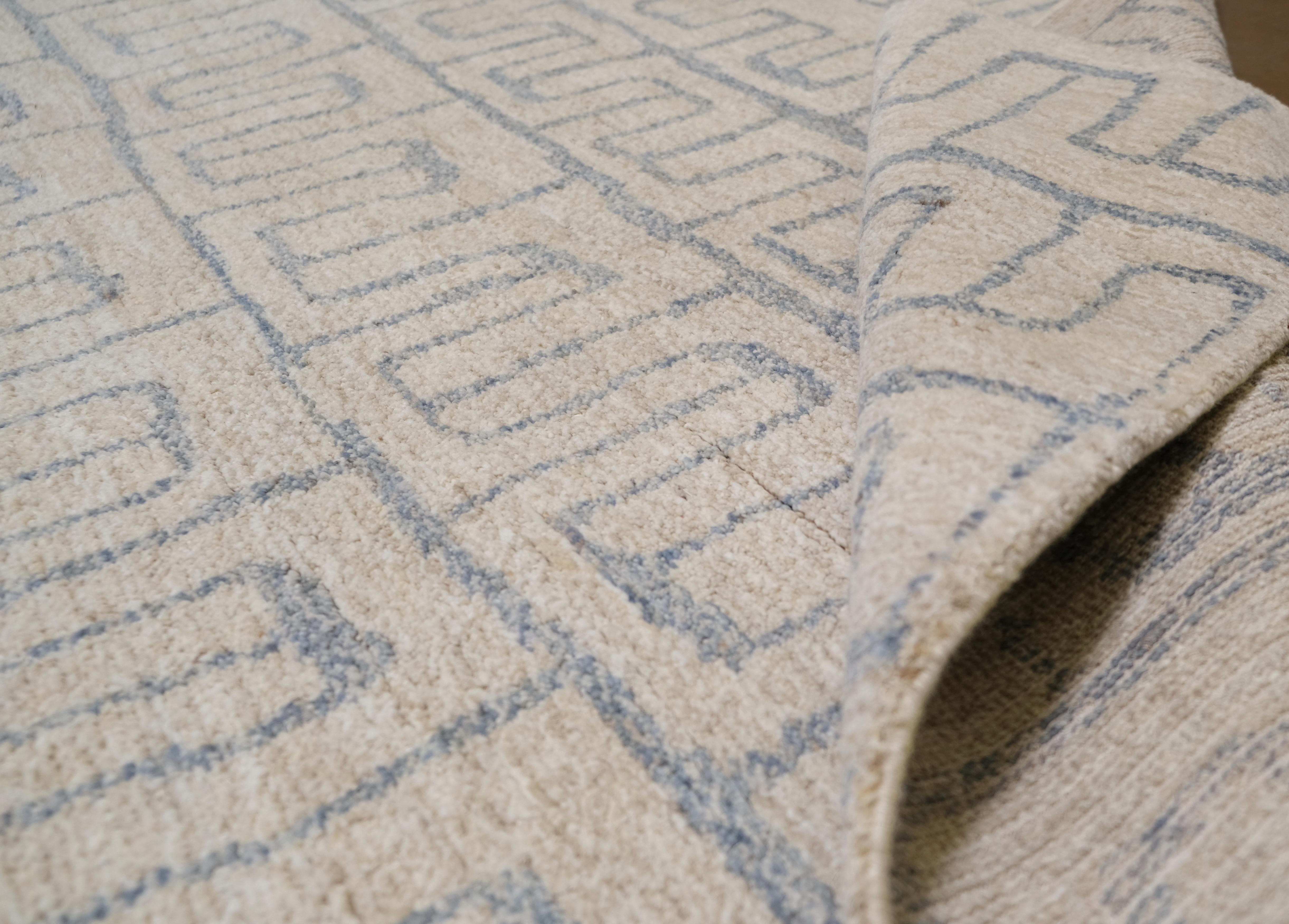 Dieser exquisite, handgeknüpfte Wollteppich aus Pakistan mit seinem fesselnden geometrischen Labyrinthmuster in beruhigenden Neutraltönen wertet Ihre Einrichtung auf. Das sich wiederholende, ineinander greifende Muster verleiht ihm ein Gefühl von