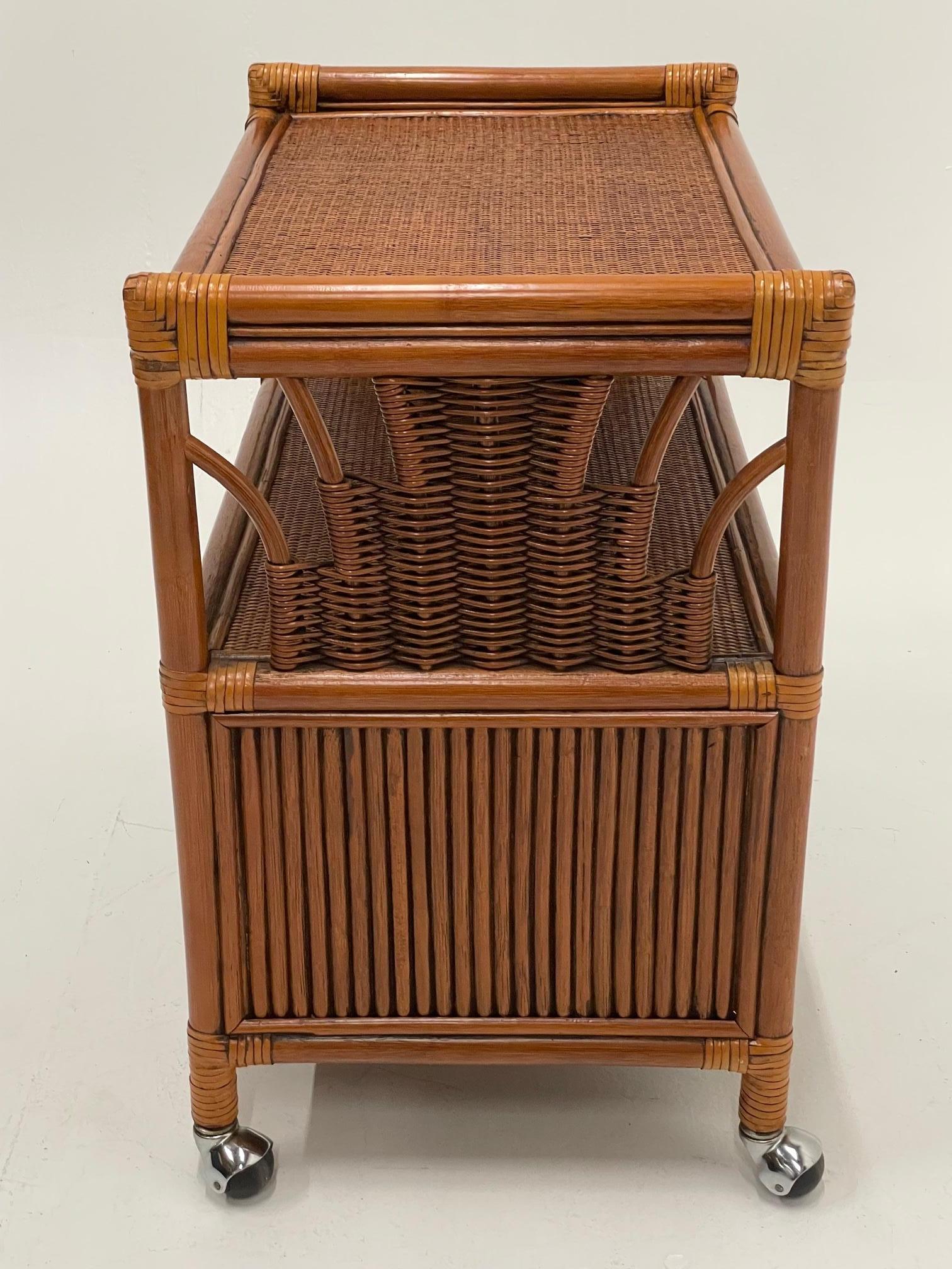 A multi functional handsome rattan server cabinet on brass casters having two tiers, lower doors that open to storage, handsome leather lace wraps, and beautiful McGuire craftsmanship.
