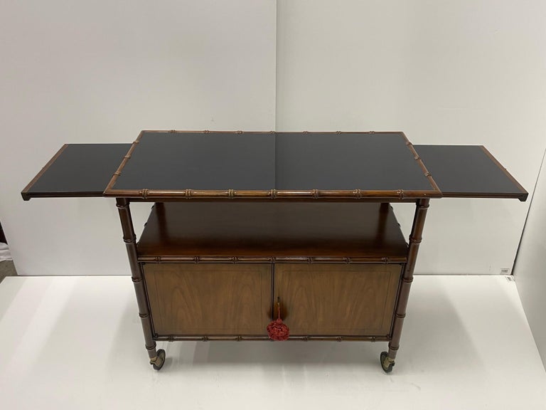 Cool Mid-Century Modern faux bamboo & mahogany multi functional sideboard server on casters having two lower doors with storage inside and a black laminated top with sliders that extend when open to 60