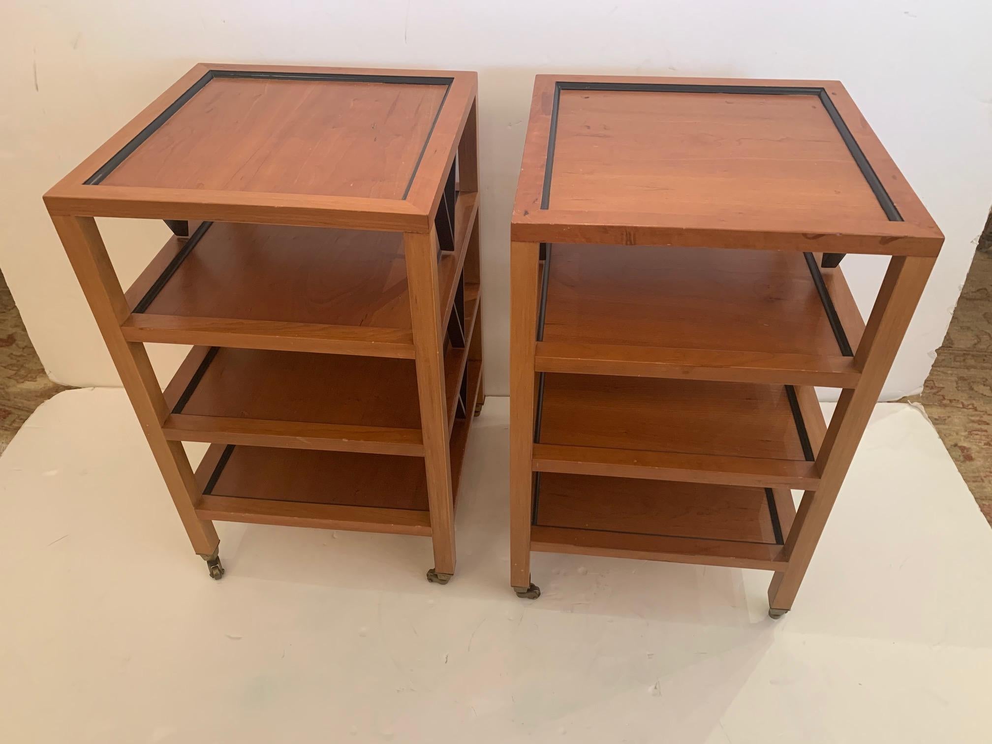 Great looking pair of square 4 tier ebony and fruitwood side or end tables having handsome color contrast and brass casters.


