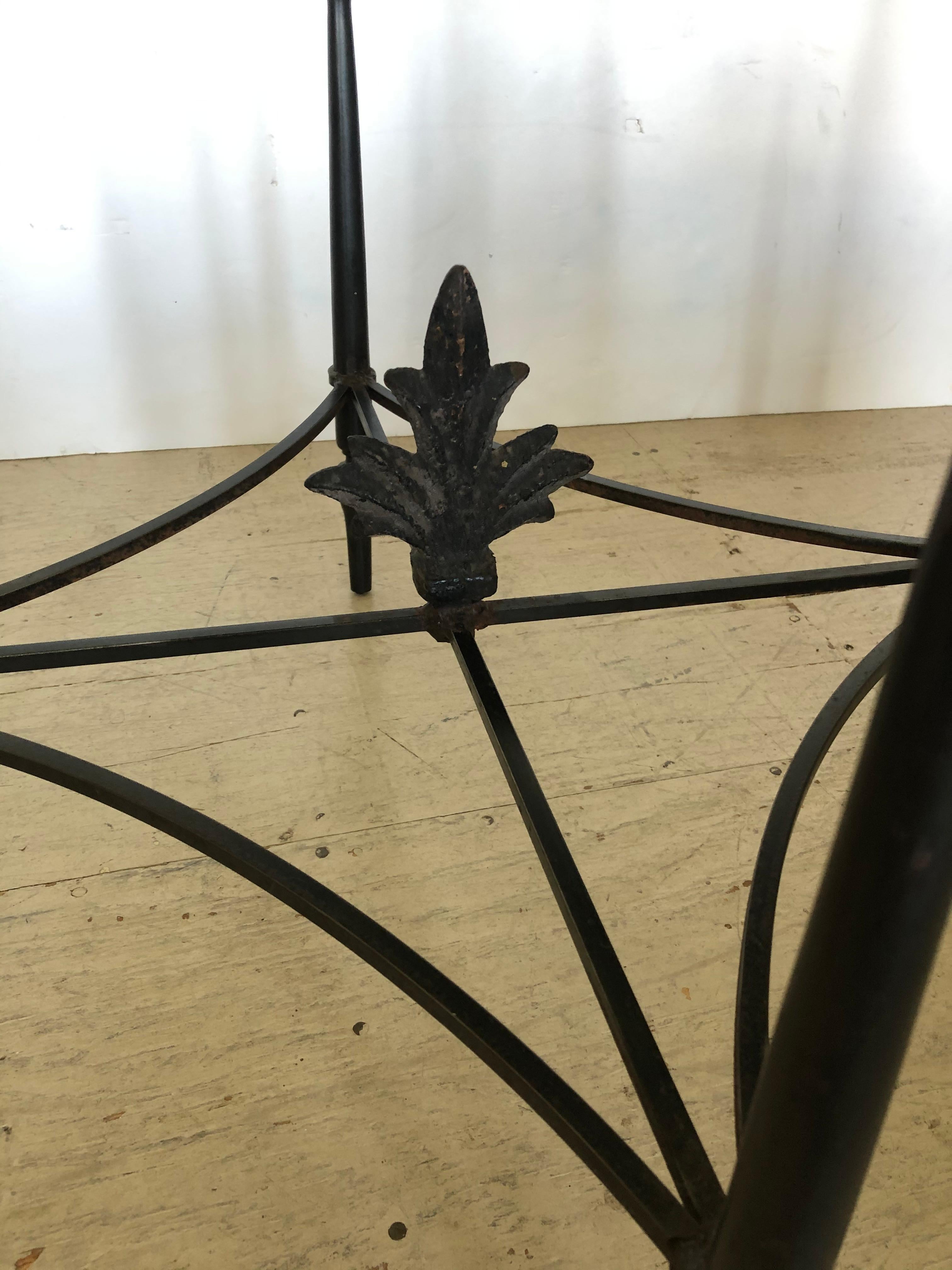A nice sized pair of round side tables having stunning wrought iron bases with central Fleur di Lis finials rising up from the stretchers, lovely shaped legs and 7/8