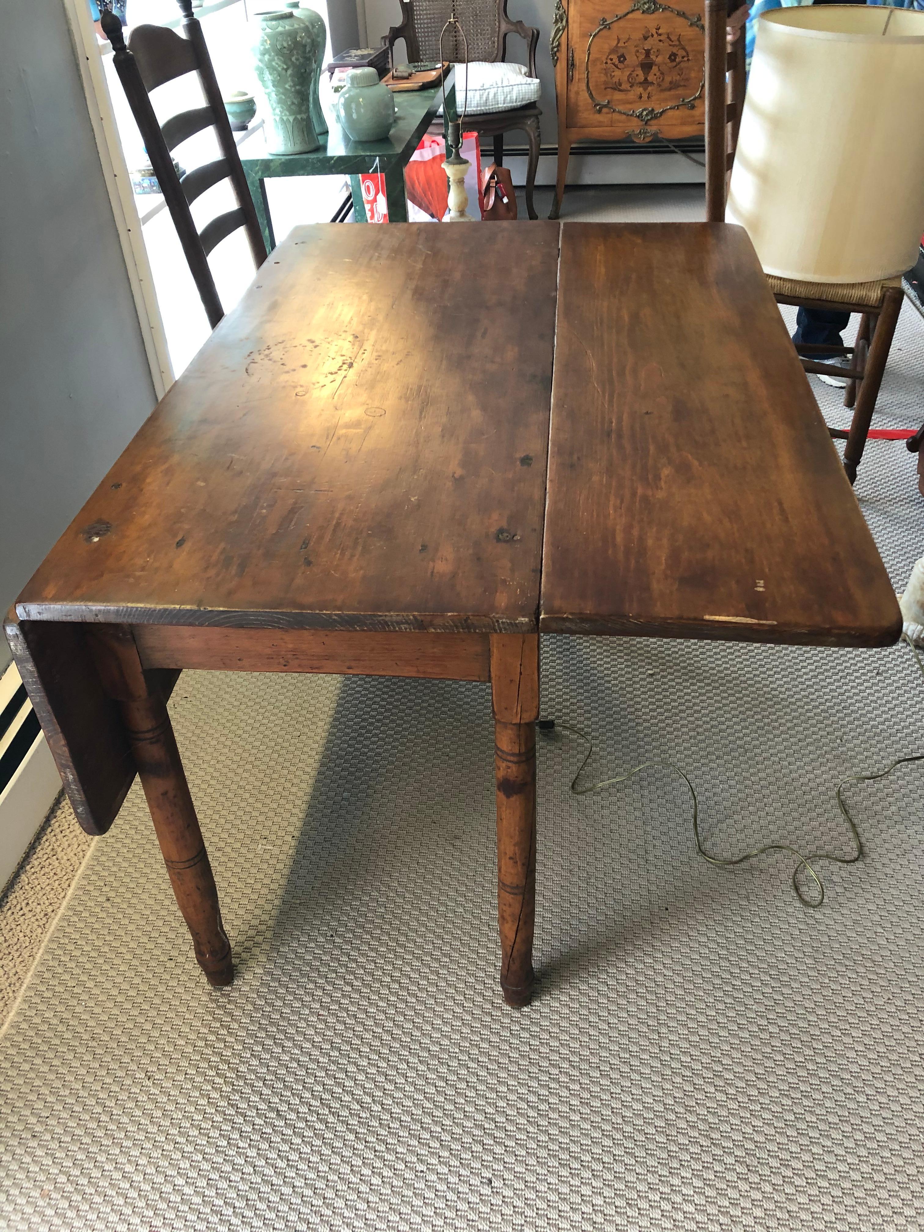 A 19th century primitive drop leaf Pembroke table having a rich aged patina and handsome turned legs. The table can serve as a small dining table when open or a side table when closed. 
Leaves are 11.5 D Open table is 40.75 x 42 x 28.25.