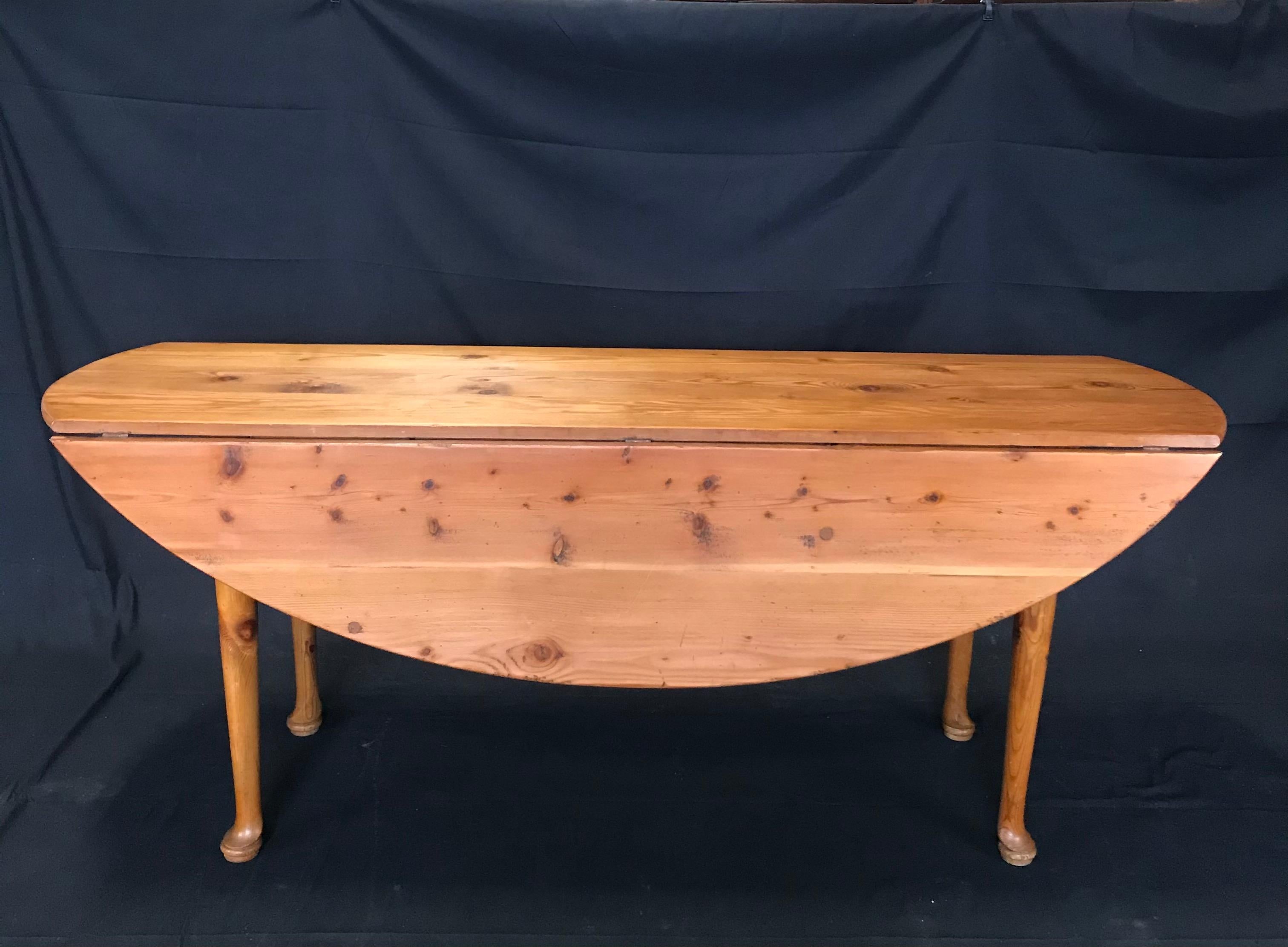 Versatile stunning Irish pine hunt or wake table in fabulous condition having four turned legs ending with hoofed bun feet. Both sides of the table are drop leaves. Once the leaves are upright the table becomes oval in shape and seats eight. When