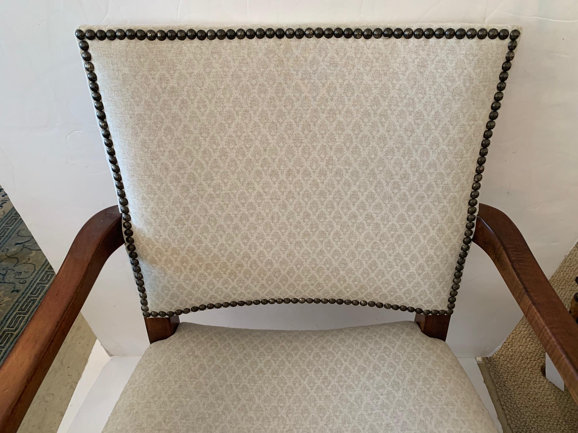 A handsome walnut and upholstered armchair, perfect for a desk or extra transitional chair, having cream upholstery finished with antiqued brass nailheads.