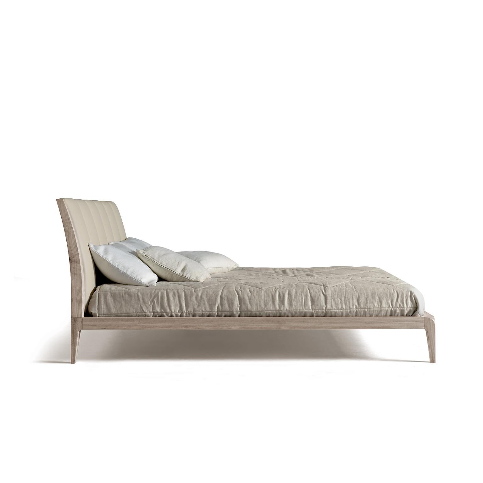 The well-proportioned bed features an upholstered headboard embellished with vertical stitching. Simple and elegant, the frame is constructed of solid, oil-finished walnut, a timeless piece that combines contemporary design with the high quality of