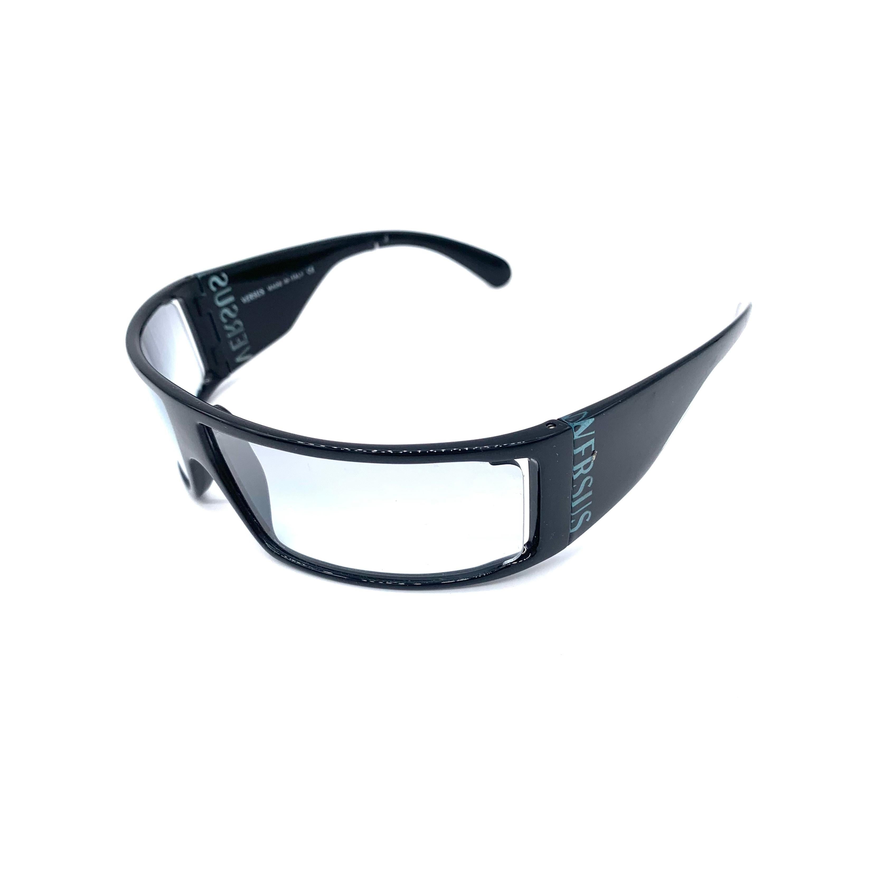 Ces lunettes de soleil Versus en acétate, classiques des années 1990, sont dotées d'une large monture noire et d'un verre transparent. Le logo Versus emblématique est placé discrètement sur le côté, ce qui en fait une déclaration de mode