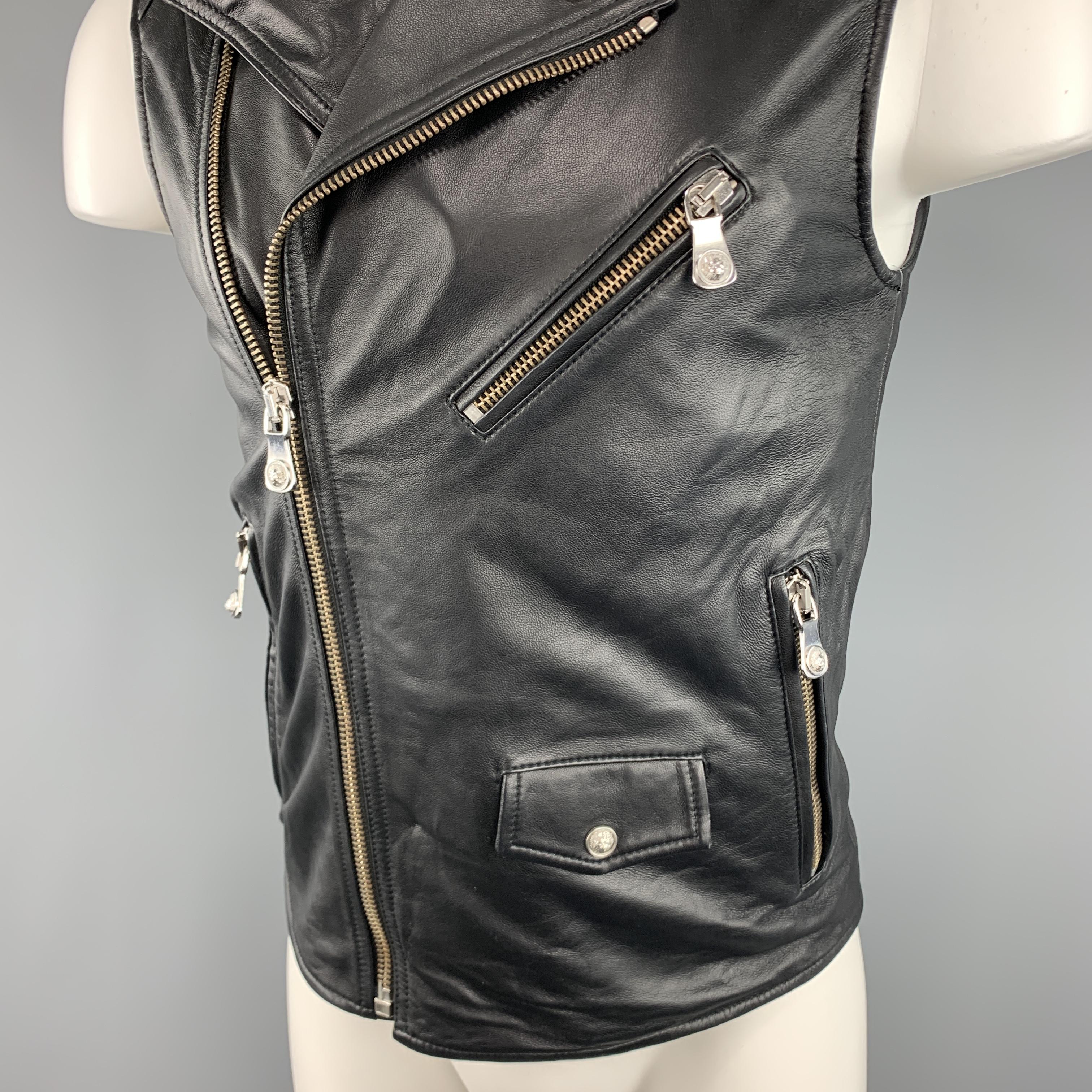  VERSUS by GIANNI VERSACE biker style moto vest come sin soft black leather with a pointed collar lapel detailed with silver tone lion head studs, three slanted zip pockets with lion head pulls, asymmetrical zip closure, and tab snap pocket. 

Very