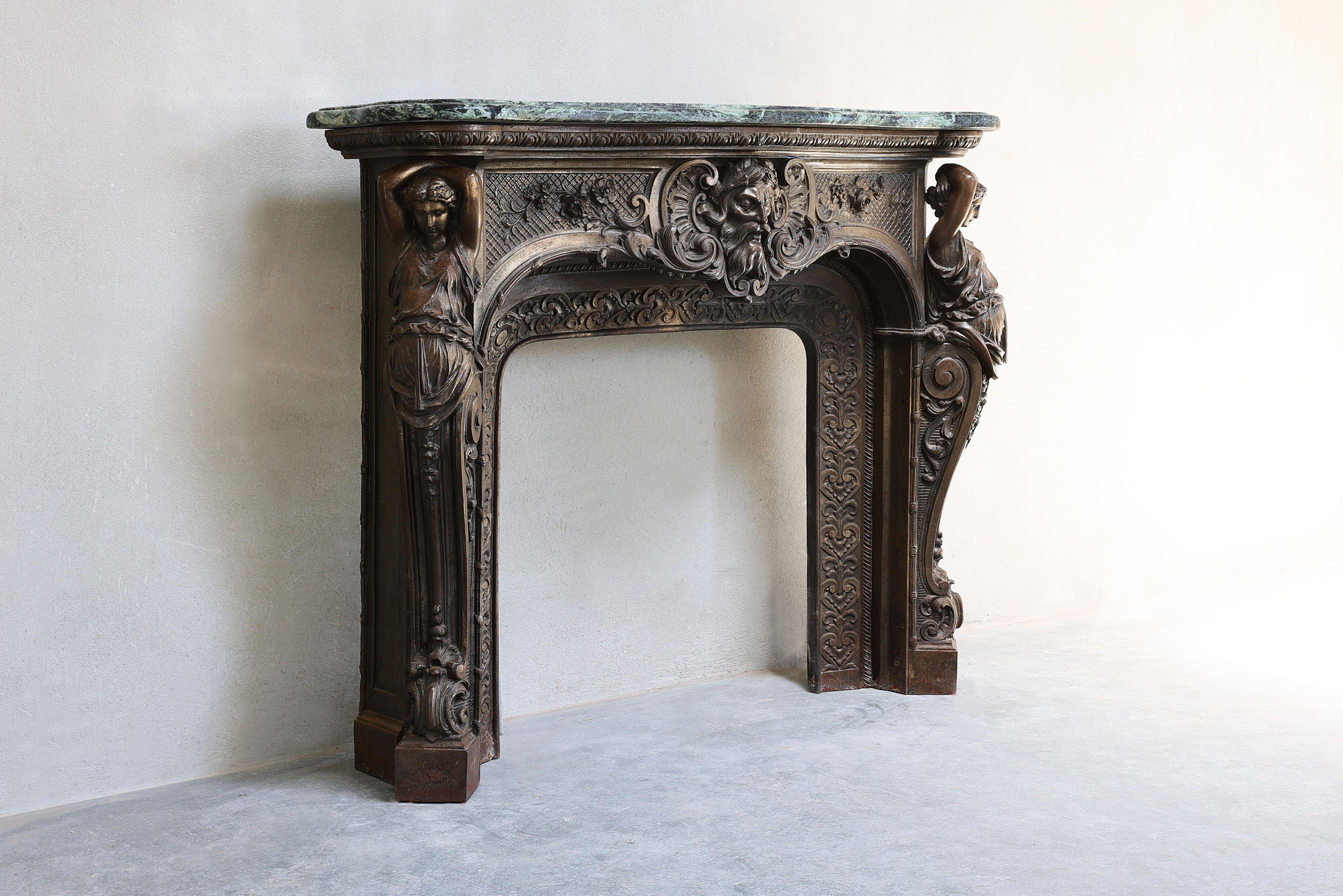 Very unique and rare antique marble fireplace of cast iron bronze patina and Vert de Gréce marble (Tinos) from the mid-19th century fireplace! The faces come from Greek mythology. In the center you see Poseidon, the God of the Sea and the statues on