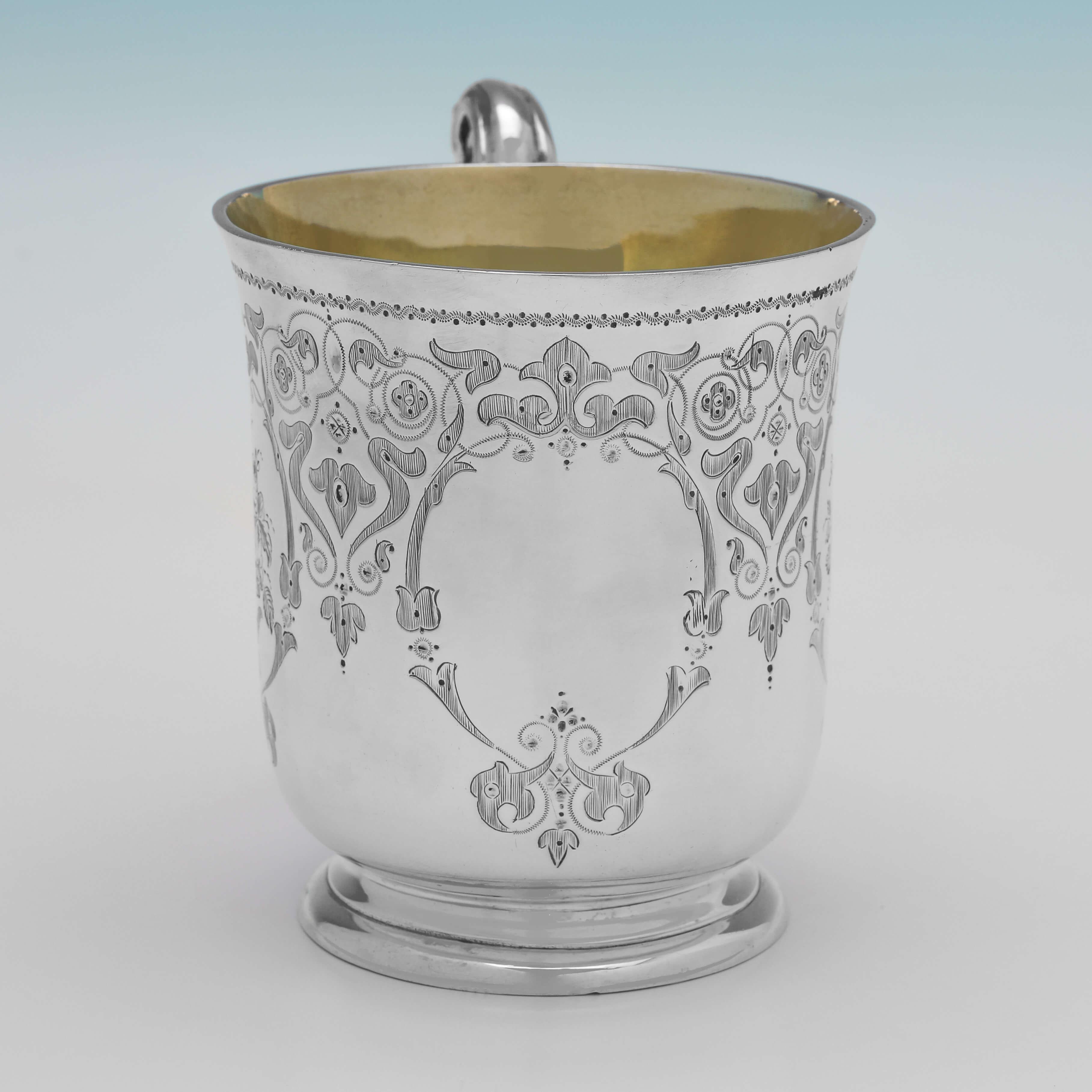 Hallmarked in London in 1863 by Edward Ker Reid, this attractive, Victorian, Antique Sterling Silver Christening Mug, features a cast ornate handle, a gilt interior, and striking engraving to the body. 

The Christening Mug measures 4