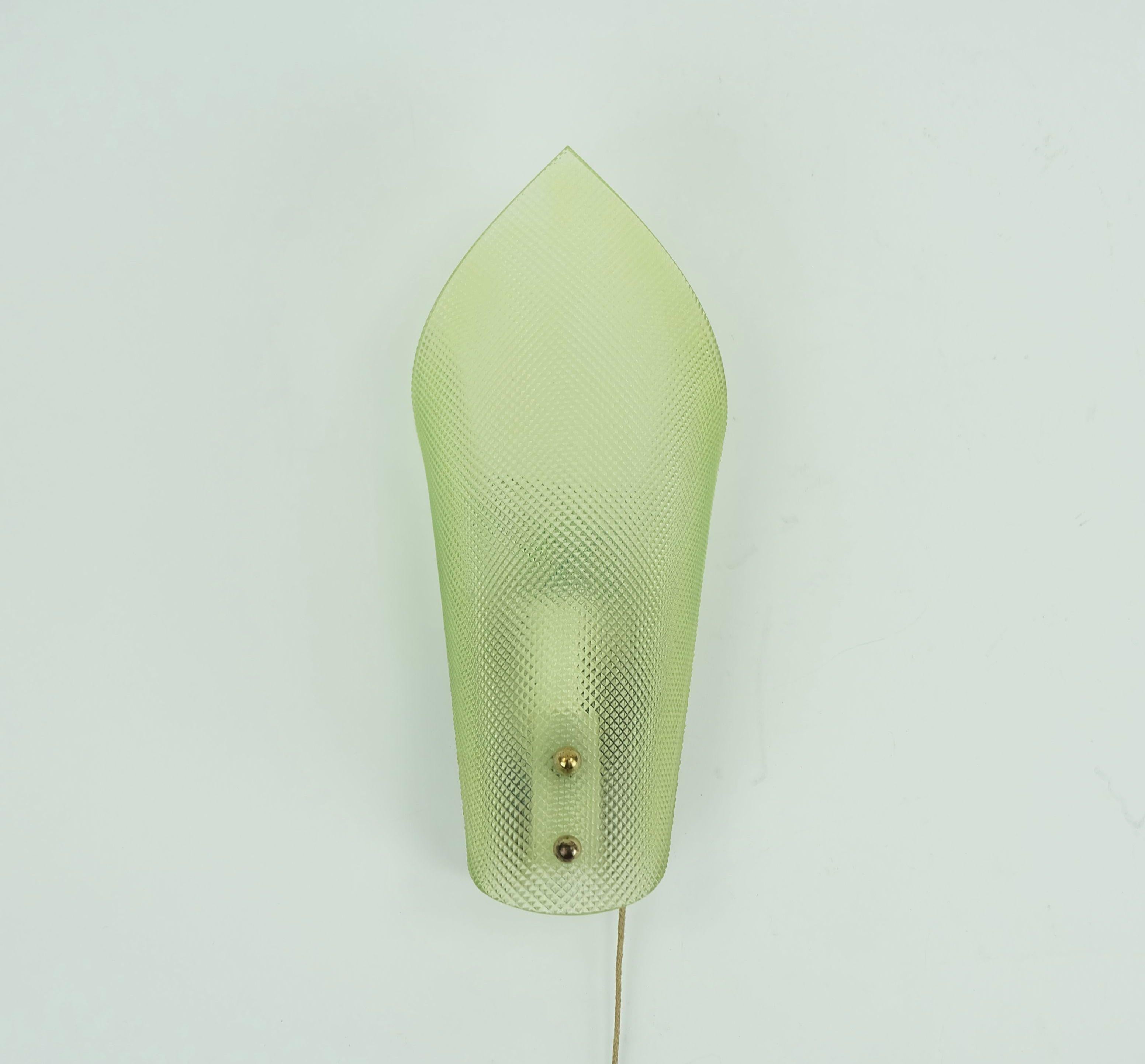Bellissima lampada da parete di piccole dimensioni degli anni '50. Il supporto da parete è realizzato in acrilico bianco, davanti al quale si trova un disco curvo in acrilico verde con una superficie rigata. Interruttore a tirante.

Dimensioni in