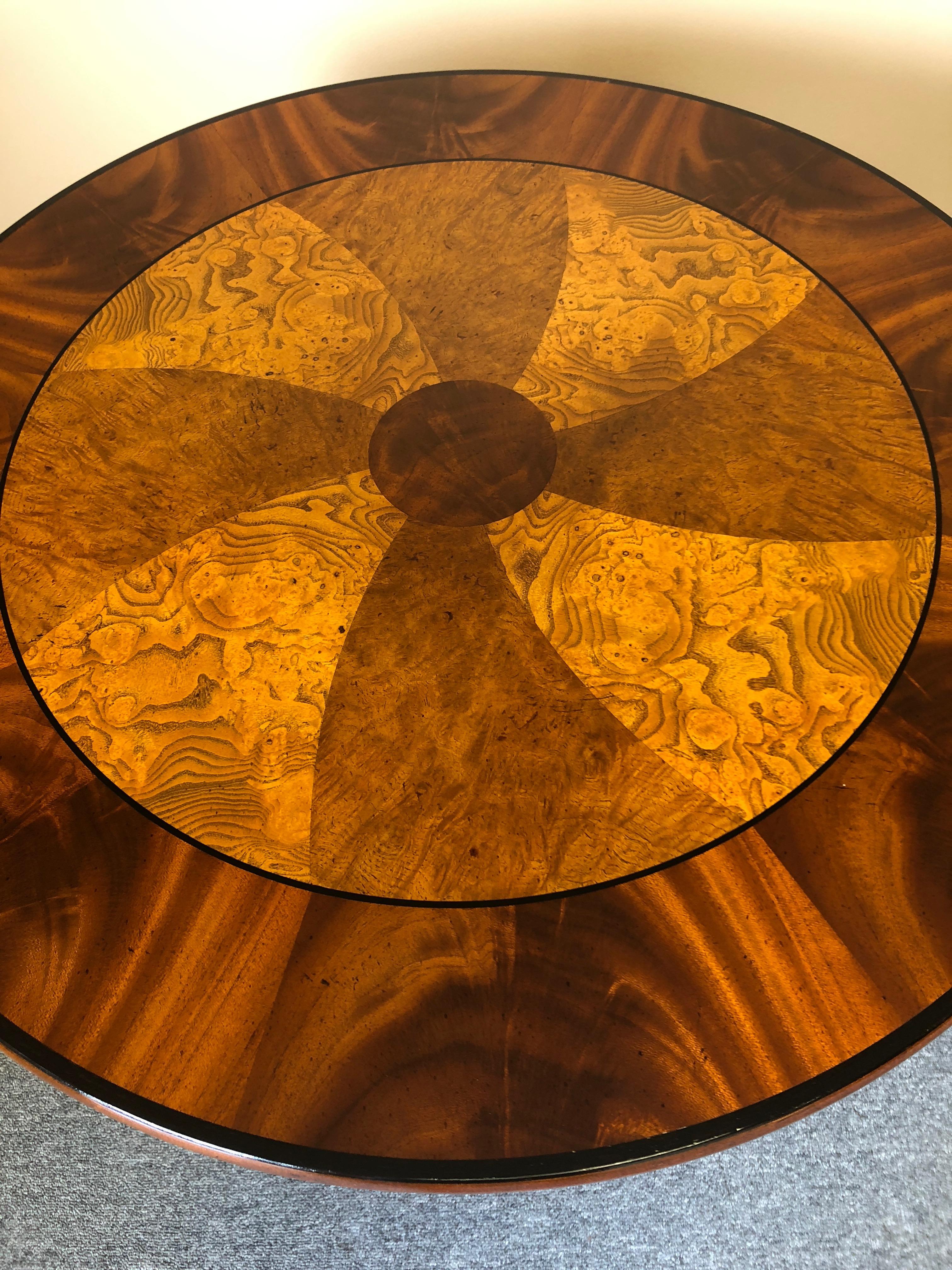 An eye-catching elegant round flame mahogany and burl side table
Having wonderful decorative pinwheel pattern on top with ebony border and decorative brass adornments including brass paw feet.