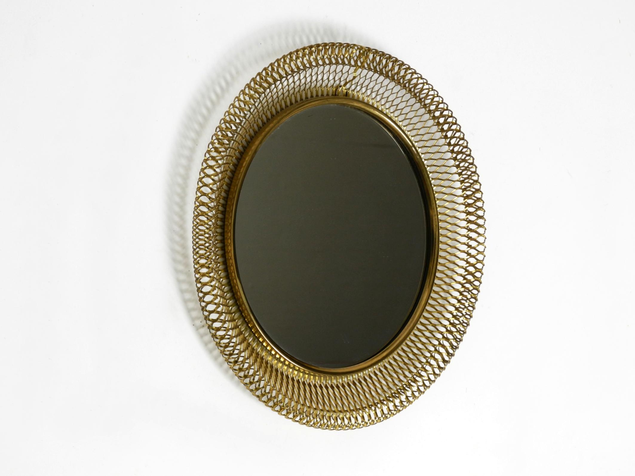 Beautiful round Mid Century Modern wall mirror with expanded brass frame and brass rim.
Stunning 1950s design in very good vintage condition.
Frame and rim are made of brass. The back plate is made of in brass color painted metal.
Mirror is not