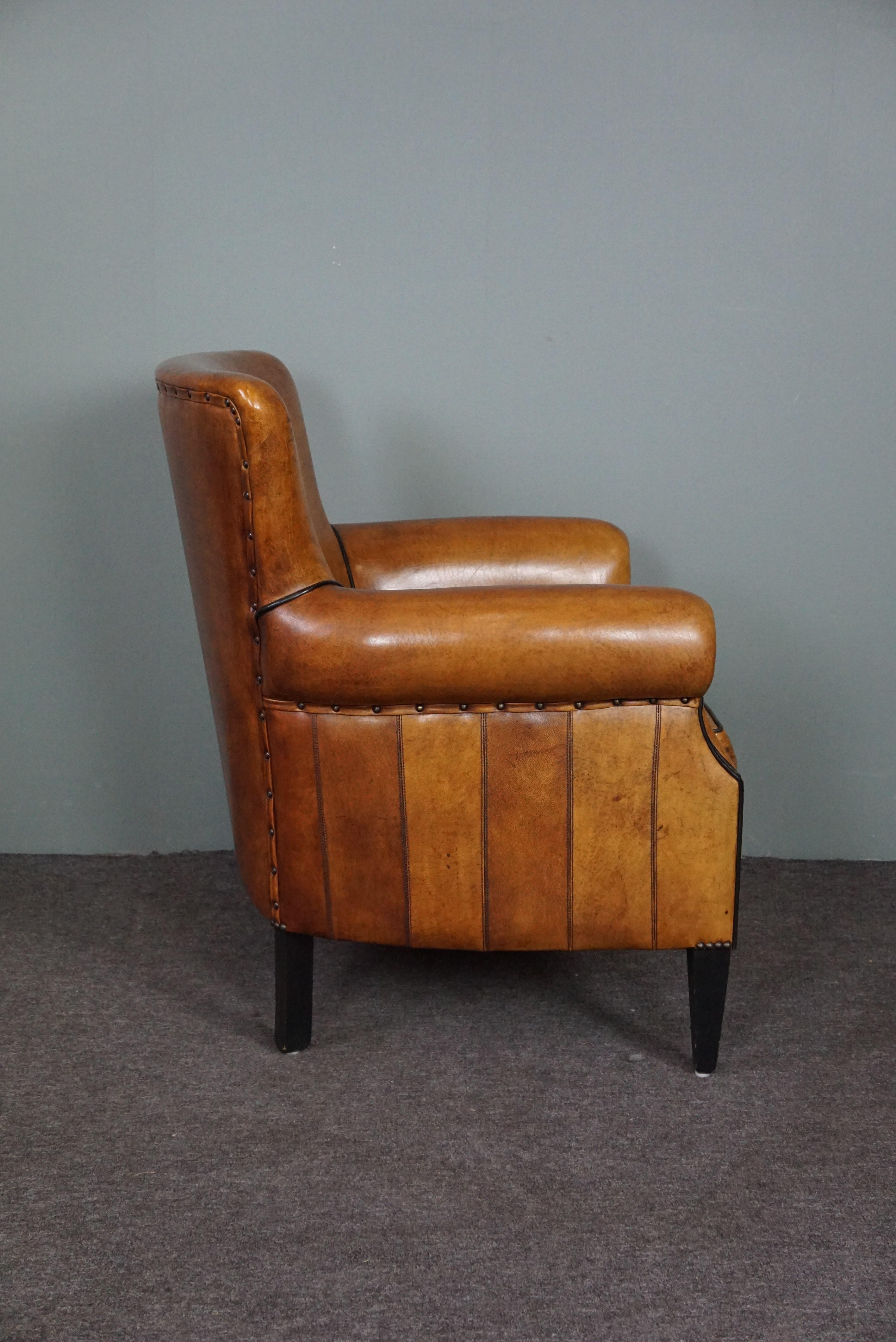 This armchair from the top brand Lounge Atelier is in very good condition and has beautiful warm colours, is comfortable to sit on and is beautifully finished with decorative nails and black piping. Characteristic of this armchair are the beautiful