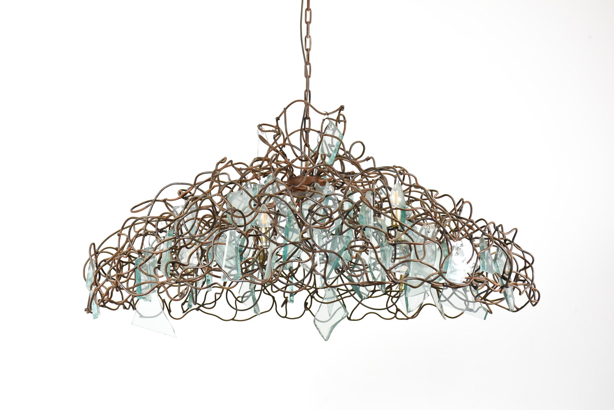 Huge, post-modern chandelier from the exclusive Dutch manufacturer Brand Van Egmond. This is the “Storm” model consisting of a hand-welded steel mesh into which several thick pieces of glass have been incorporated. 
As this chandelier design leaves
