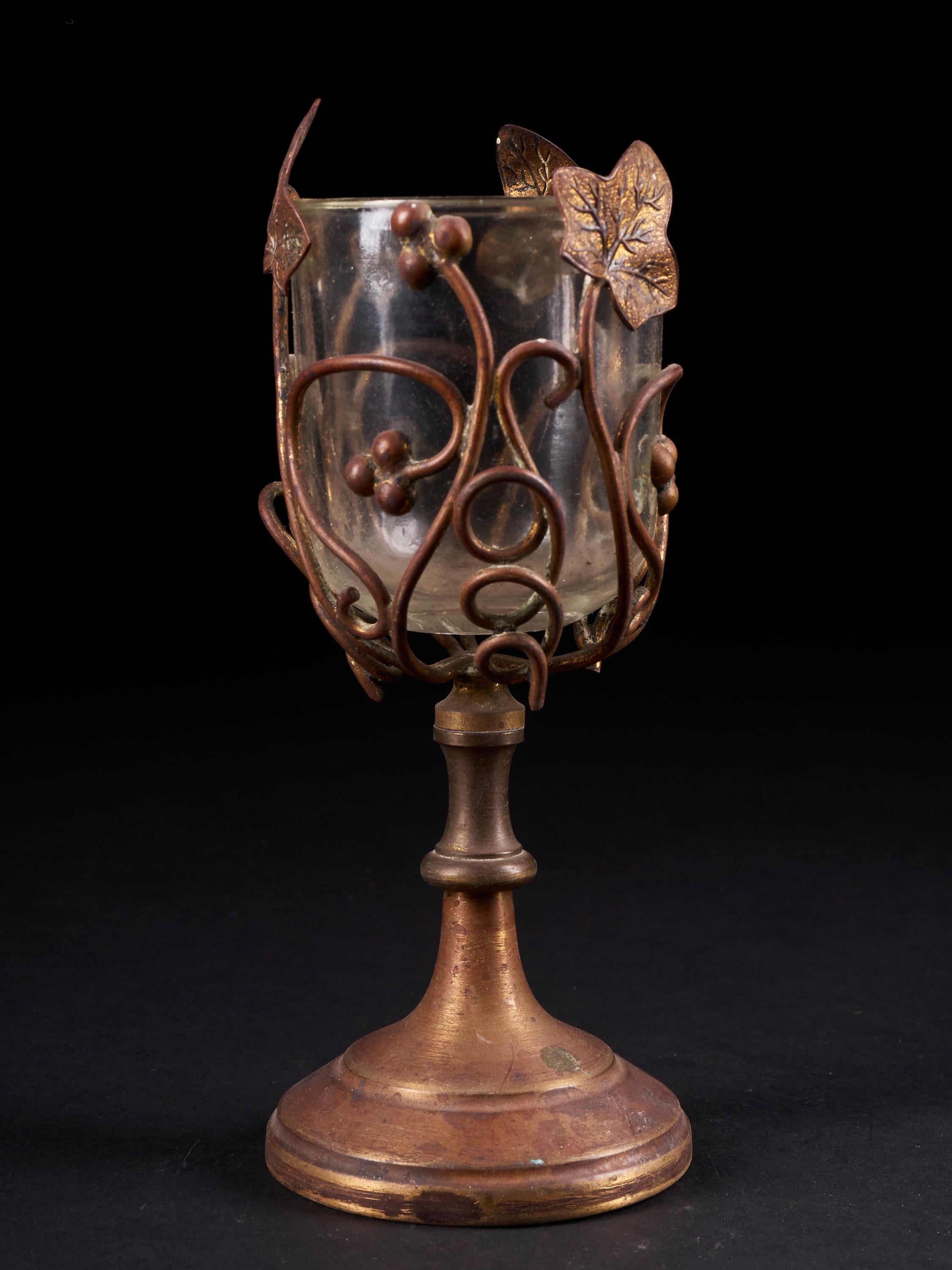 Most unusual wineglass made of glass and supported by a copper alloy foliage structure and a smooth stand, tagged AC in the glass bowl.