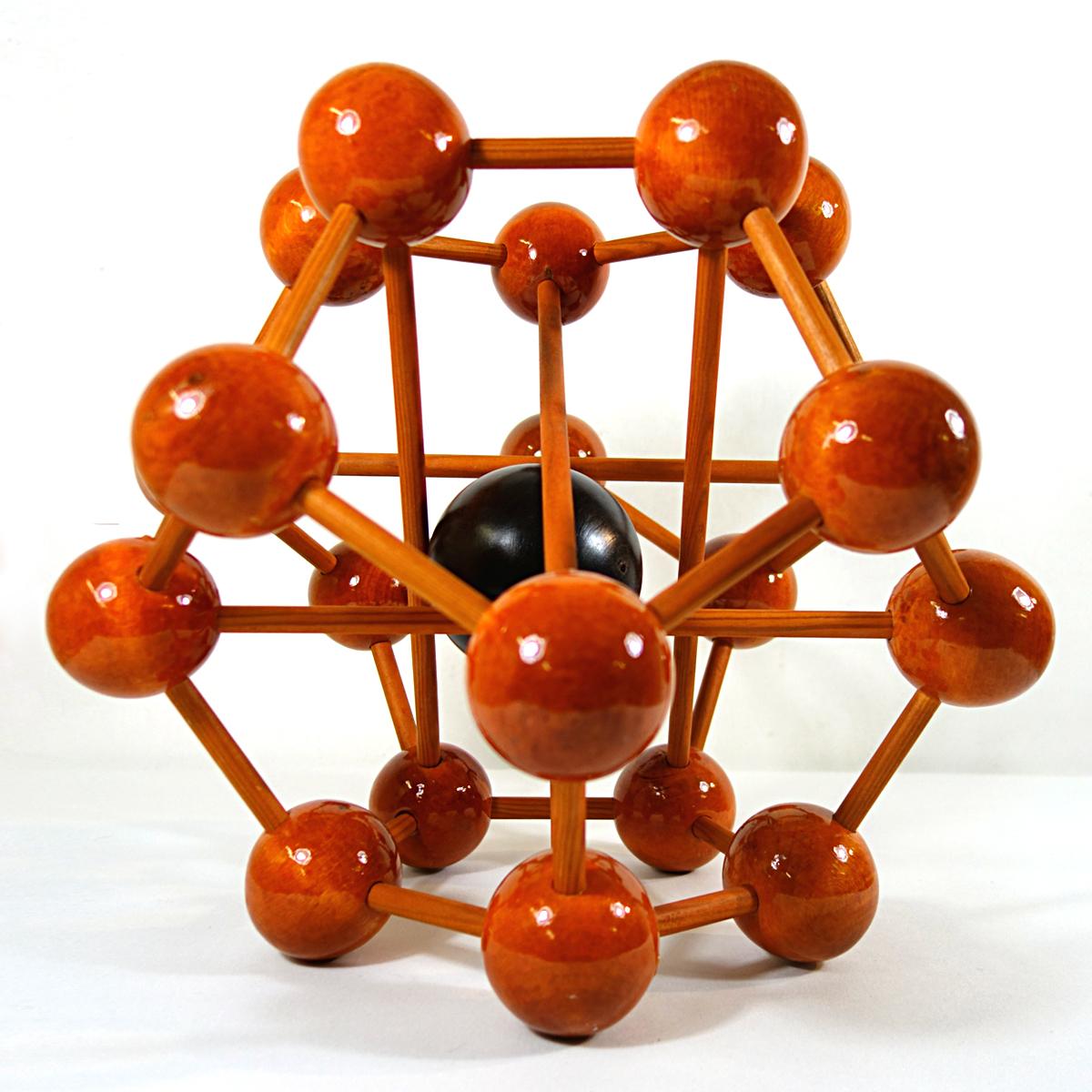 Diese große Miniaturversion eines Atoms enthält 20 Kugeln auf 4 Ebenen, also 5 Kugeln pro Ebene. Sie sind mit Holzstäben verflochten. Im Herzen des Atoms befindet sich eine größere, bewegliche Kugel aus einer dunkleren Holzart.
Dieses Atom aus der