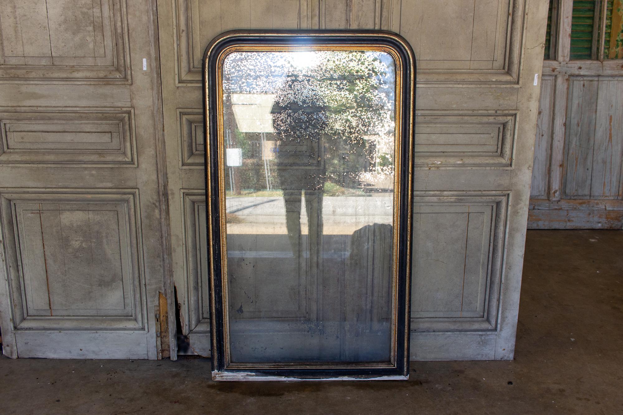 This is a very distressed antique French Louis Philippe mirror with a painted black and gilt frame. Losses to the frame throughout, and the mirrored surface has deteriorated in the most beautiful way. Obviously, this piece doesn't function as a tru