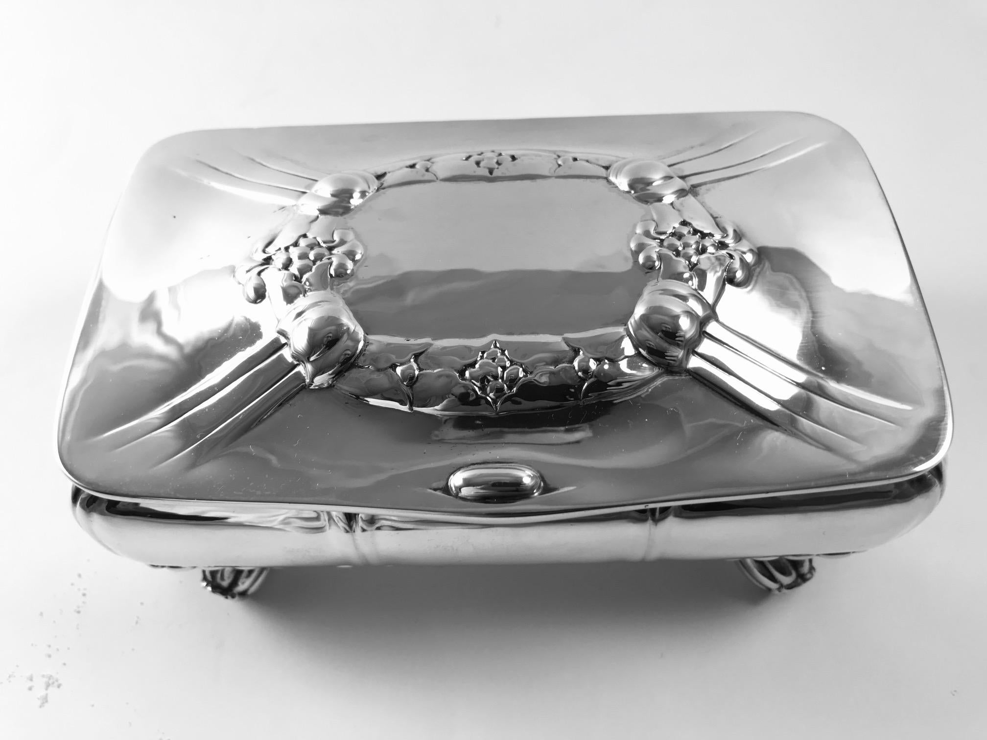 This is a good sized Georg Jensen 830 silver box, ornately decorated with eight large floral buds as feet, design #133 by Georg Jensen.

The box has a wooden lining and measures 6? x 3 1/2? x 2 3/4? (15cm x 9cm x 7cm). Gross weight including the