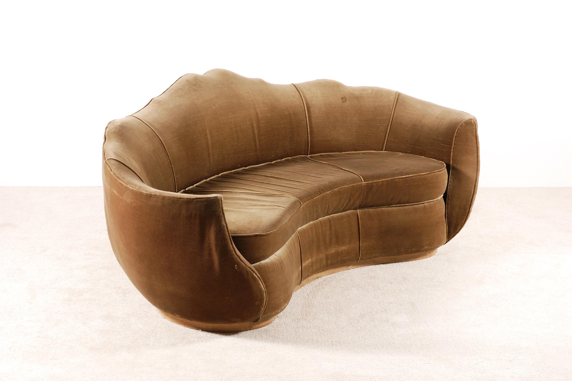 Here is a very elegant three-seat curved Art Deco sofa with generous carved lines and voluptuous curves, typical from the French Art Deco period. Massive curved Beech wood base, France, 1930s.

The original green/brown velvet upholstery is aged