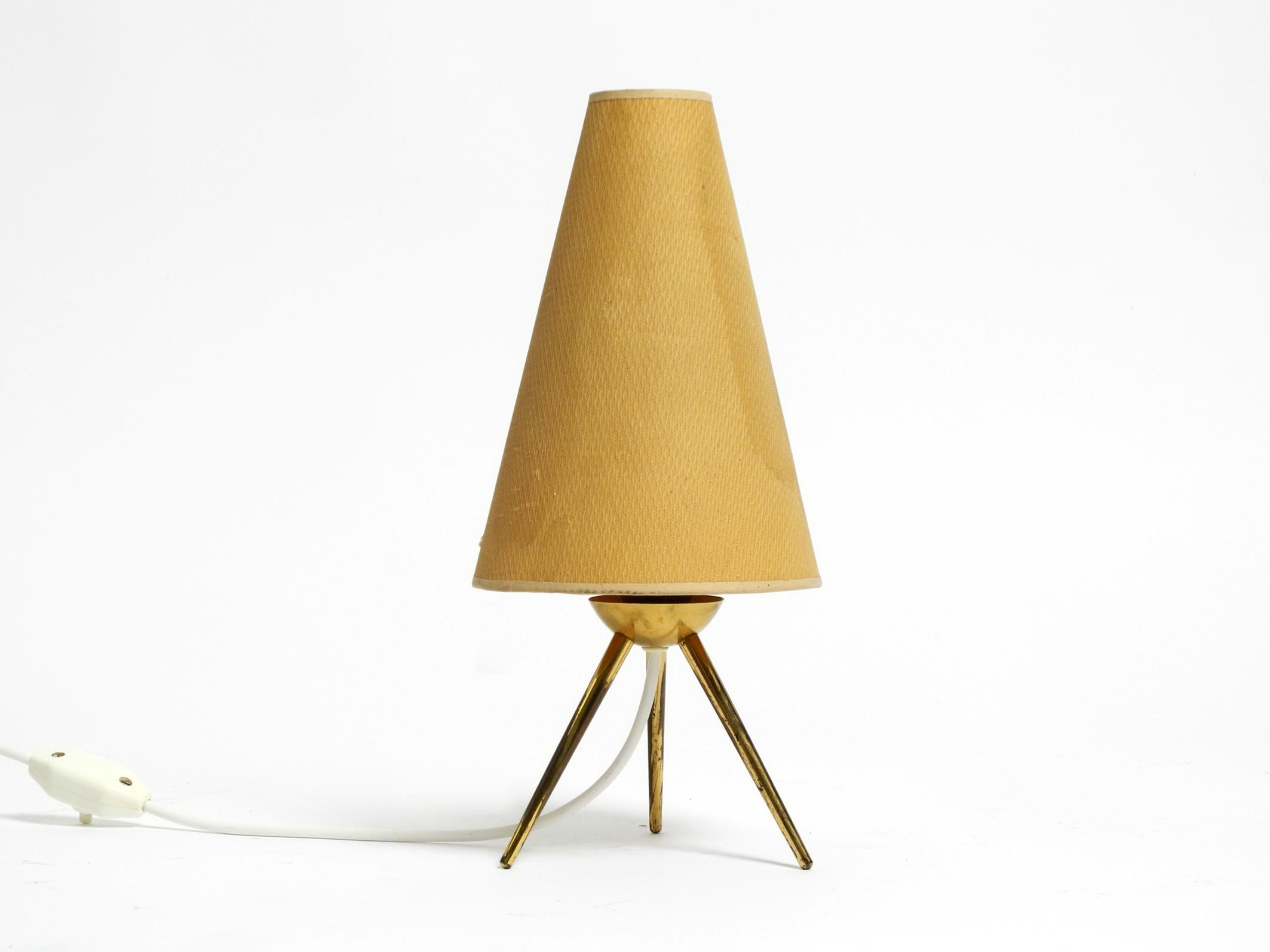 Very elegant original Mid Century Modern brass tripod table lamp with original lampshade.
Beautiful typical 1950s design made entirely of brass.
Very good vintage condition and fully functional.
Slight signs of wear on the lamp.
No damage to the