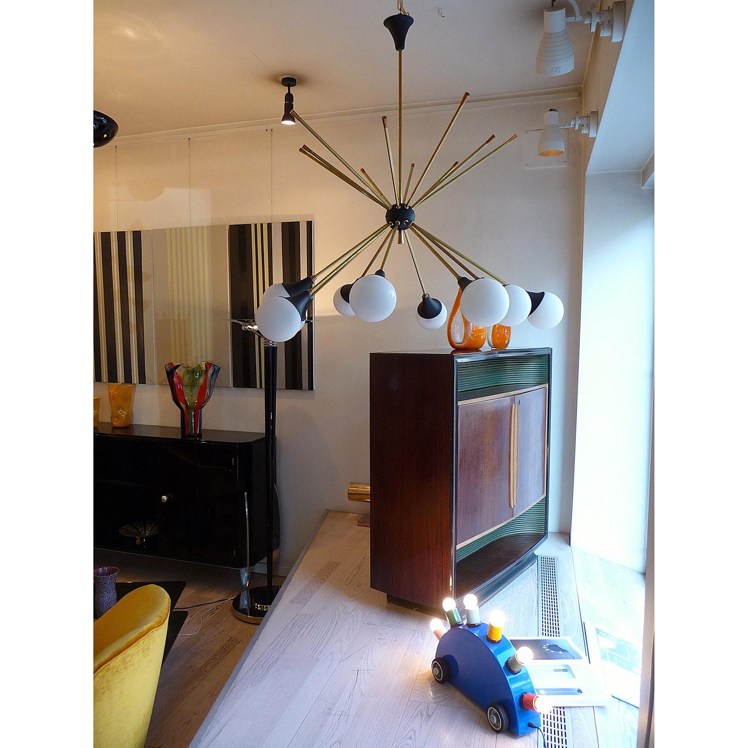 Italian chandelier, Mid-Century Modern style, 10 arms, each ending with a glass shade.
Elegant ten arms chandelier made of brass, painted metal and opaline glass ball-shades. For the US we'll deliver it with E12 bulb bases.
Standard delivery in