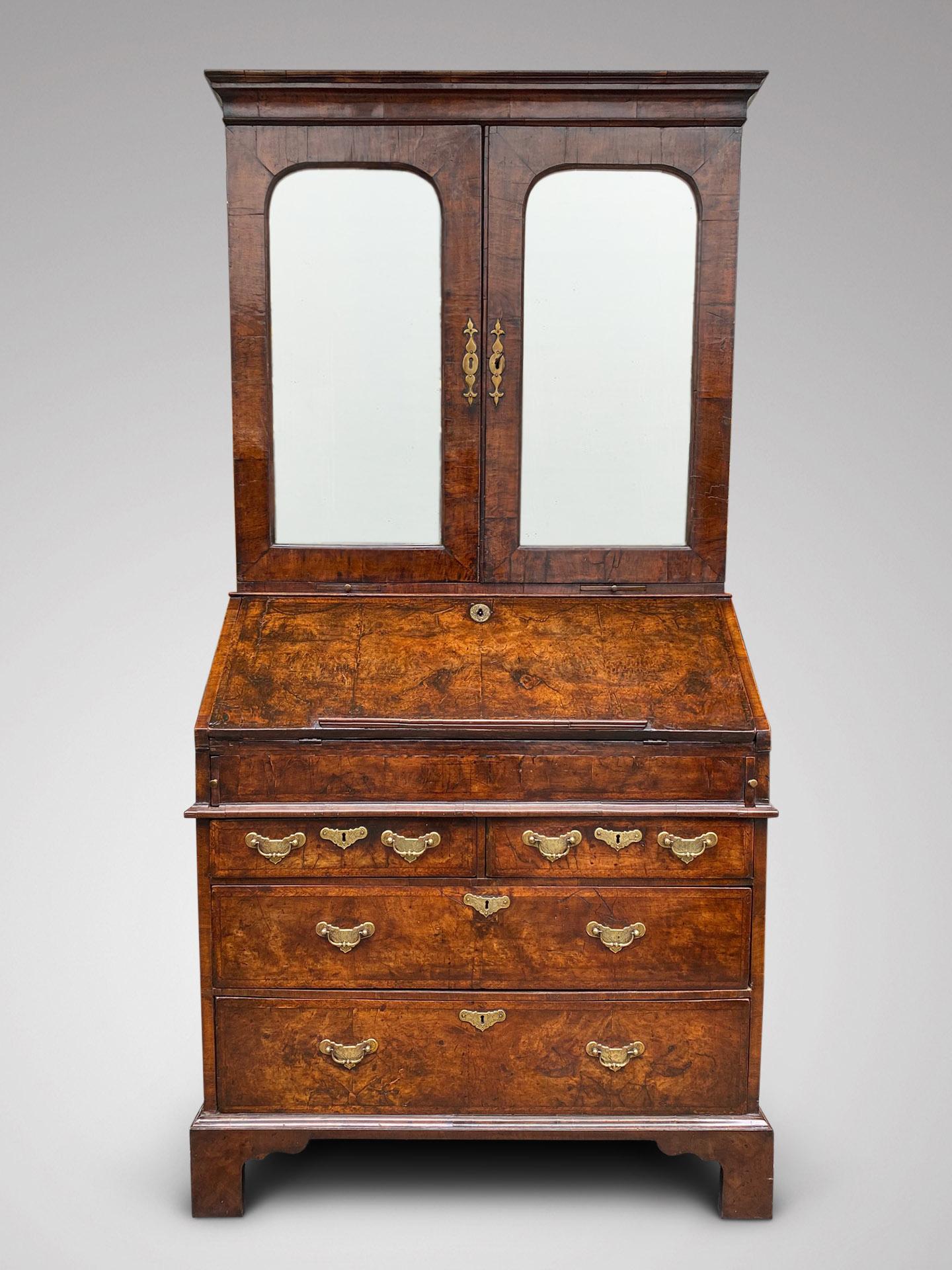 A very fine George I period walnut and feather banded bureau bookcase, circa 1720, the moulded cornice above a pair of mirror panelled doors, opening to an adjustable shelf section above an arrangement of pigeon holes, three small drawers and a pair