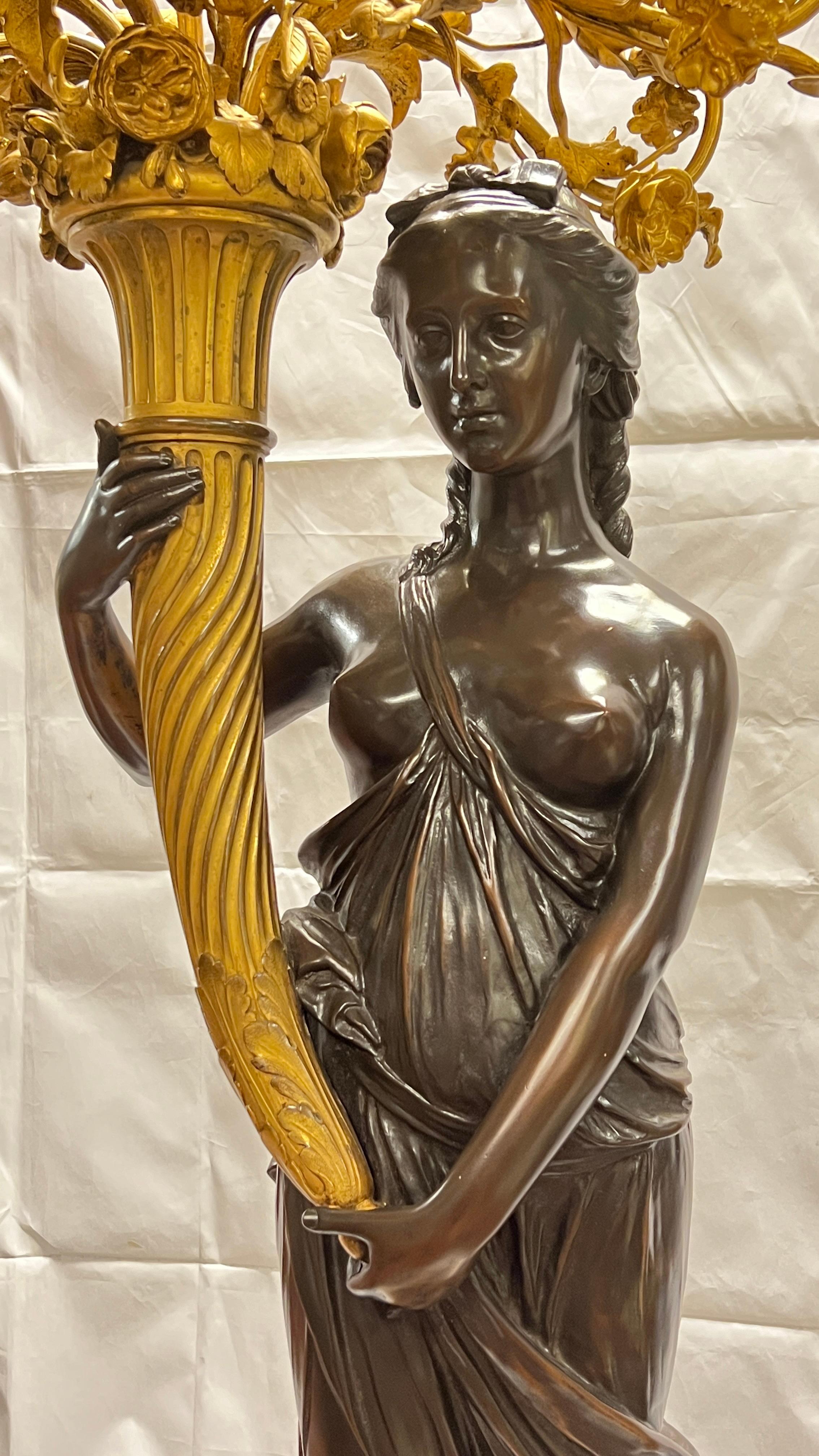 Chandelier monumental français du 19e siècle en bronze finement sculpté et coulé, à patine brun foncé, représentant une jeune fille néoclassique tenant un grand candélabre émanant d'une corne d'abondance, et reposant sur un piédestal massif sculpté