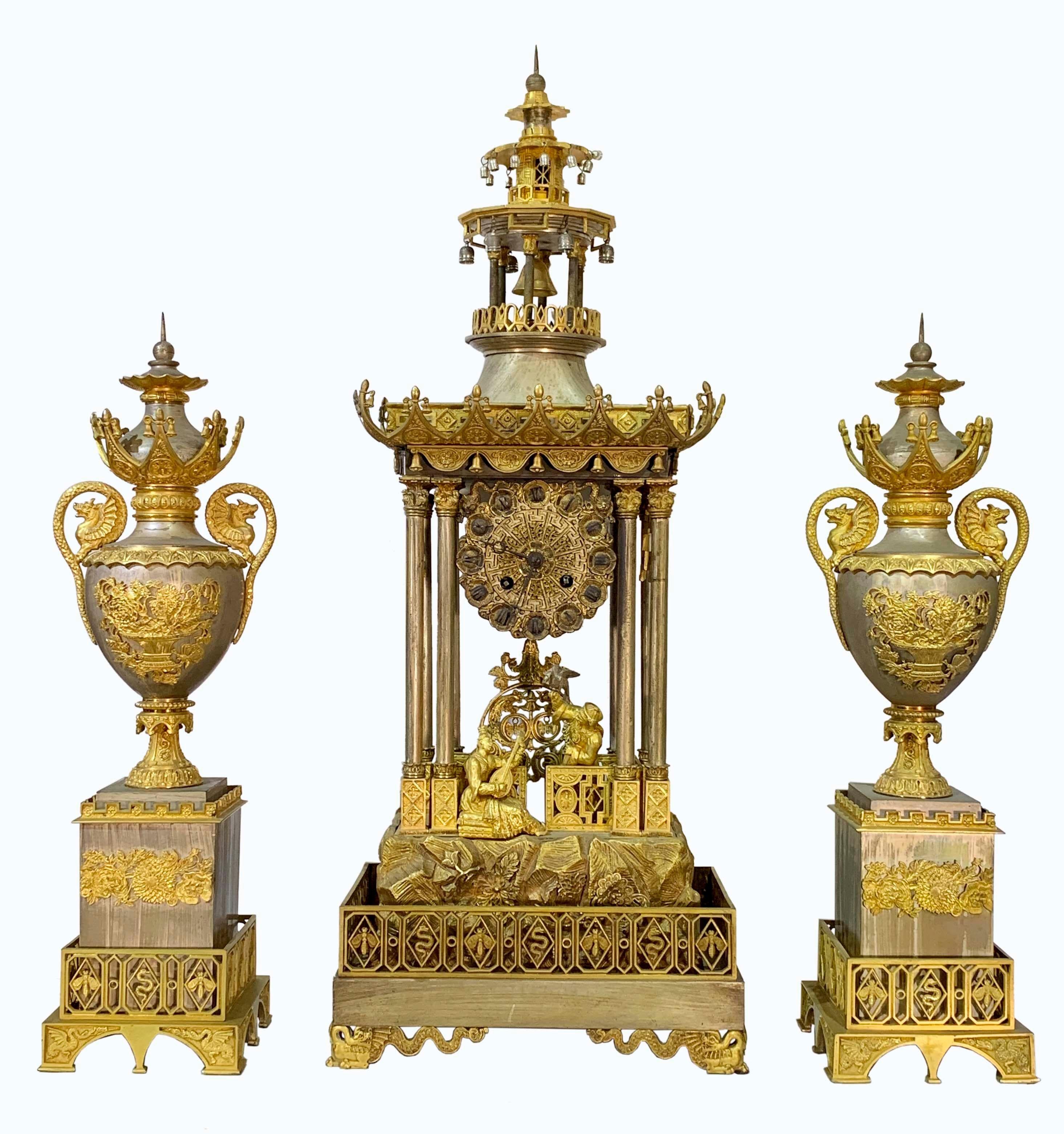An important & rare silvered and gilt bronze 3-piece Chinoiserie clock garniture comprising a clock and two side pieces. The Pagoda form clock with 2 Chinese figures, one sitting playing the mandolin and the other standing with a bird on his arm,