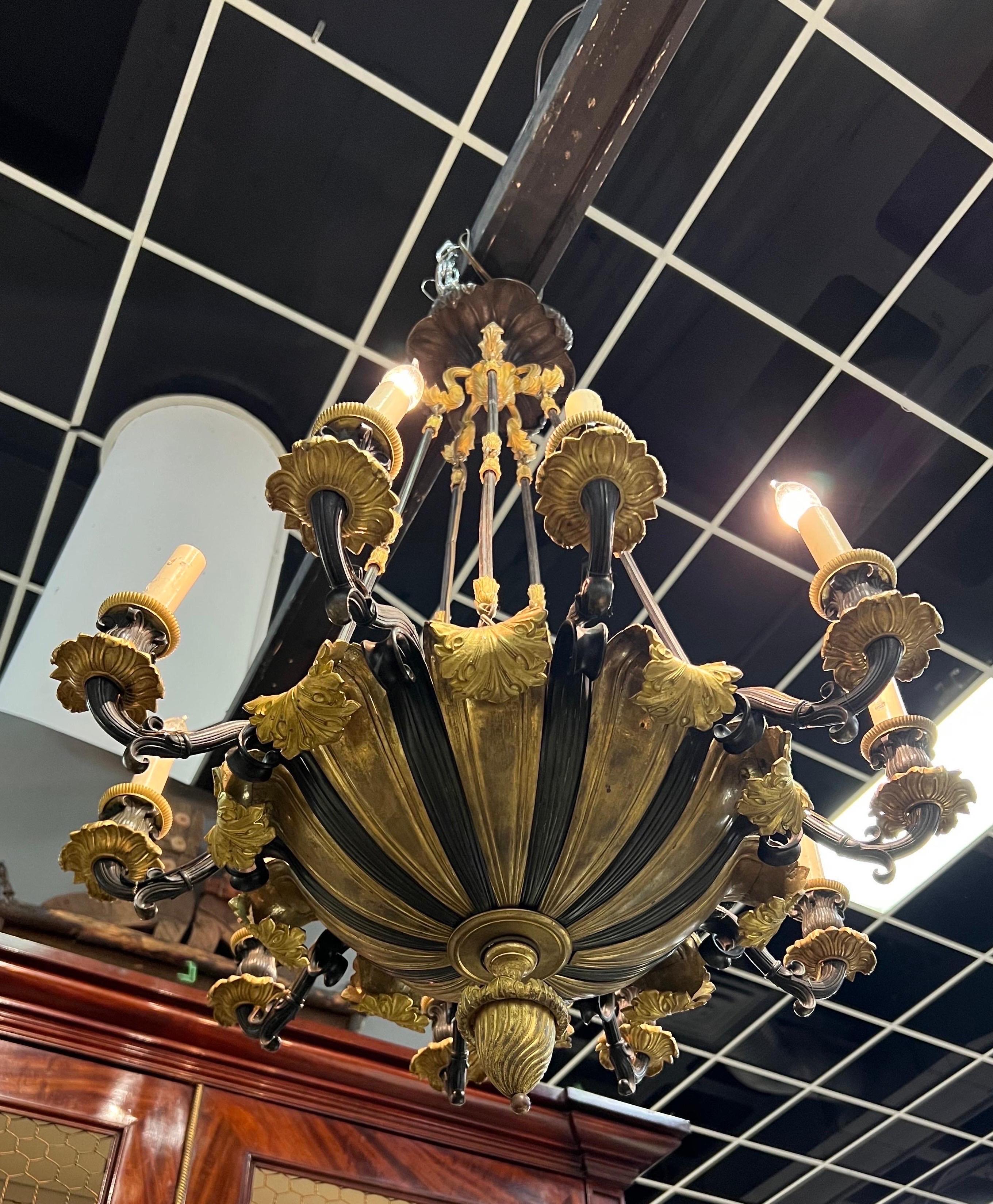 Incroyable lustre empire français en bronze du 19ème siècle, maintenant électrifié. 10 bras patinés séparés par des bronzes à décor doré se terminant en feuilles. 