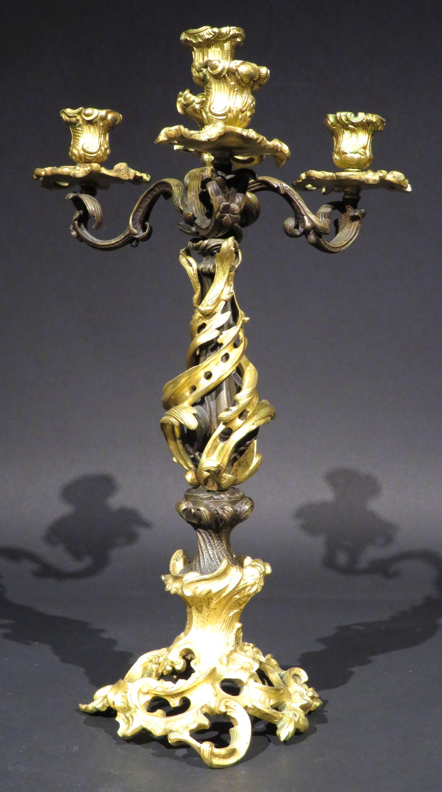 A stunning & superbly cast 19th century parcel gilt candelabrum in the Rococo taste, showing a sculptural central column of entwined bronze & parcel gilt bronze, rising from a pierced rocaille gilt bronze base to three foliate cast branches fitted