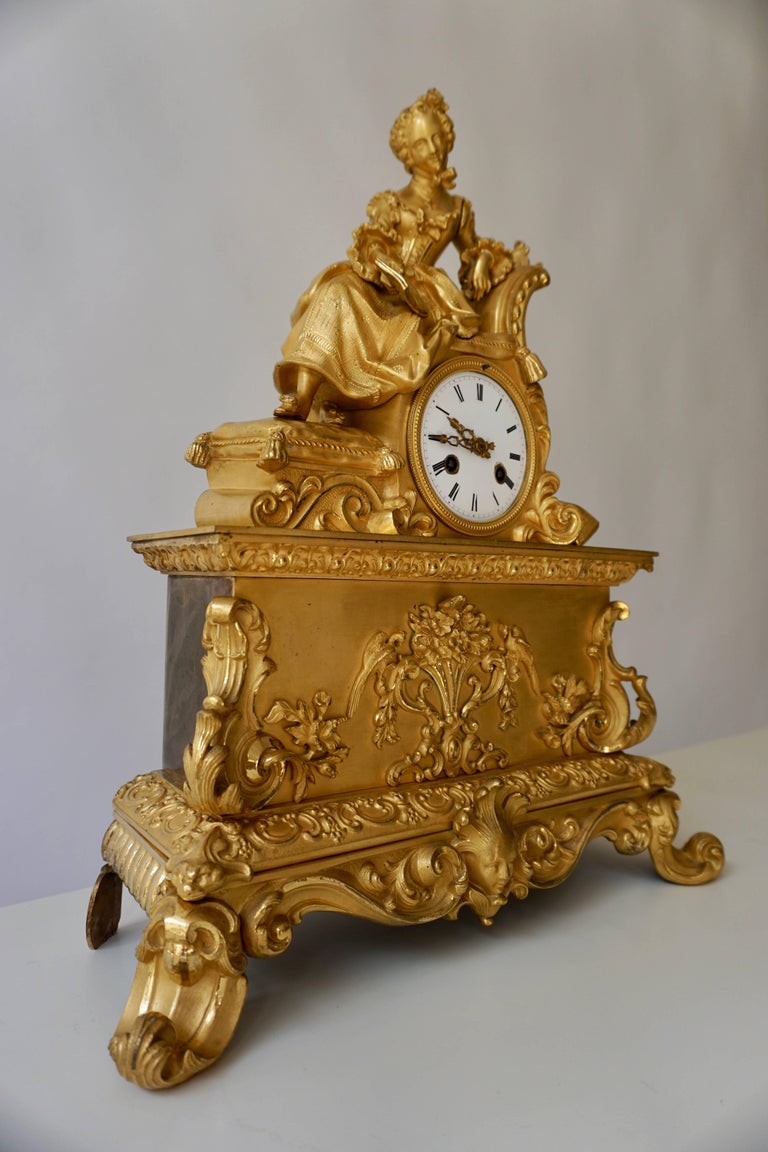 A very fine and elegant fire, gilt bronze mantle clock in the romantic taste, the base resting on scroll feet connected with leafy volutes centered by a female mask under a decorated frieze showing animal heads on the corners, the pediment with a