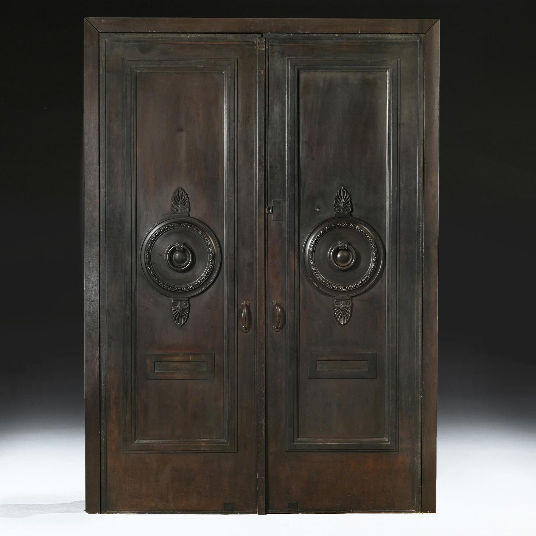 A Wonderful Pair of Imposing Bronze Entrance Strong Doors of the Finest Quality 
English Circa 1900
Of bronze over a core of mahogany, classical in style, a circular wreath centred by a ring handle suspended from a hinge embellished with rose, above