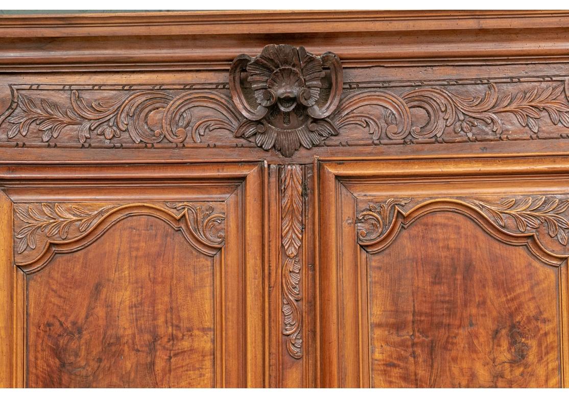 A grand traditional French antique armoire in solid cherry wood. The Double Doors with handsome sectioned Burl Panels framed by well-carved Foliate Designs. The top section with central Shell Carving framed by more Foliate designs. Pegged