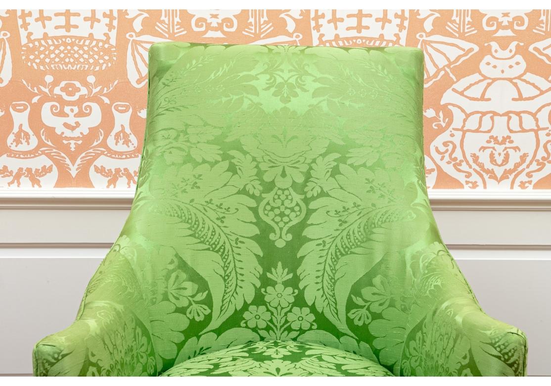 Armchair covered in luxurious custom green silk damask fabric having sloping and sinuous arms, angular backrest, loose down or feather filled pillow seat, turned front legs with brass casters and saber back legs.
Dimensions: 27 1/2