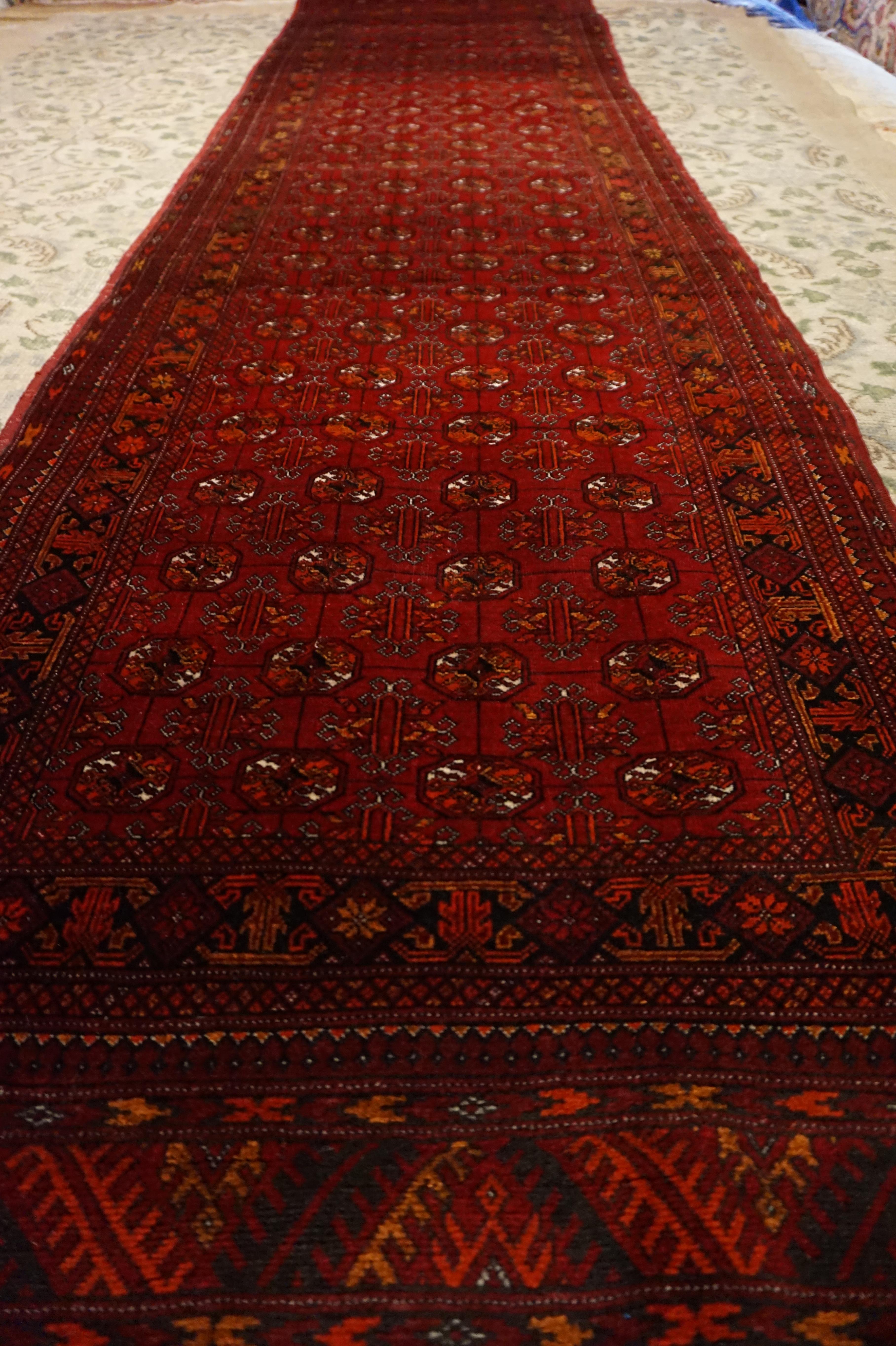 Antique Turkmen Bokhara runner in excellent condition. Densely knotted high quality wool runner with deep shades of crimson, orange and copper. Some variegation present. In overall good condition.