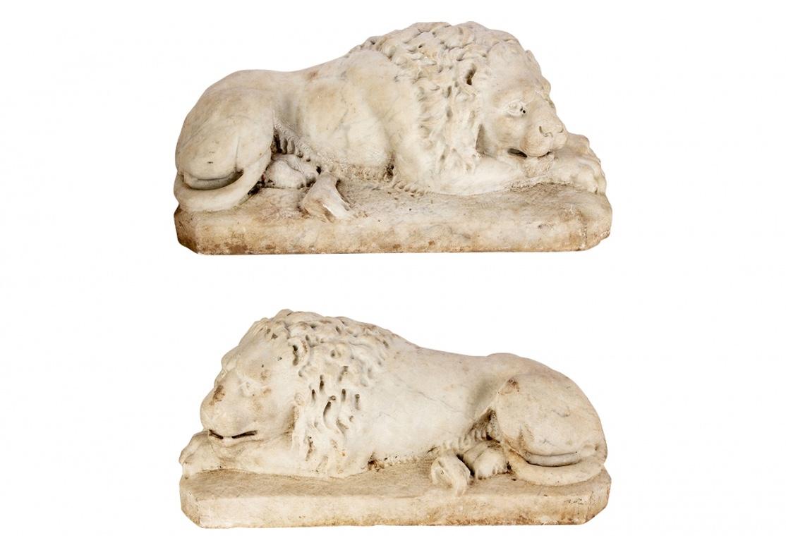 Recumbent adorsed life- like lions with aroused aspect. With finely carved details with drill holes in the manes, pupils and underbelly fur. In the manner of ancient Roman or Renaissance carved stone lions. Rectangular bases with canted corners.