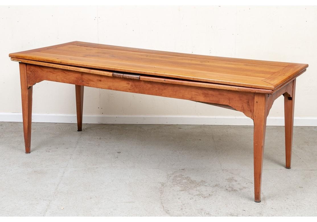 An extraordinary antique French farm table with self-storing leaves and return. The long banded plank constructed top with two long enclosed leaves and a single pull out return on one end. With a shaped frieze and raised on square tapering legs. In