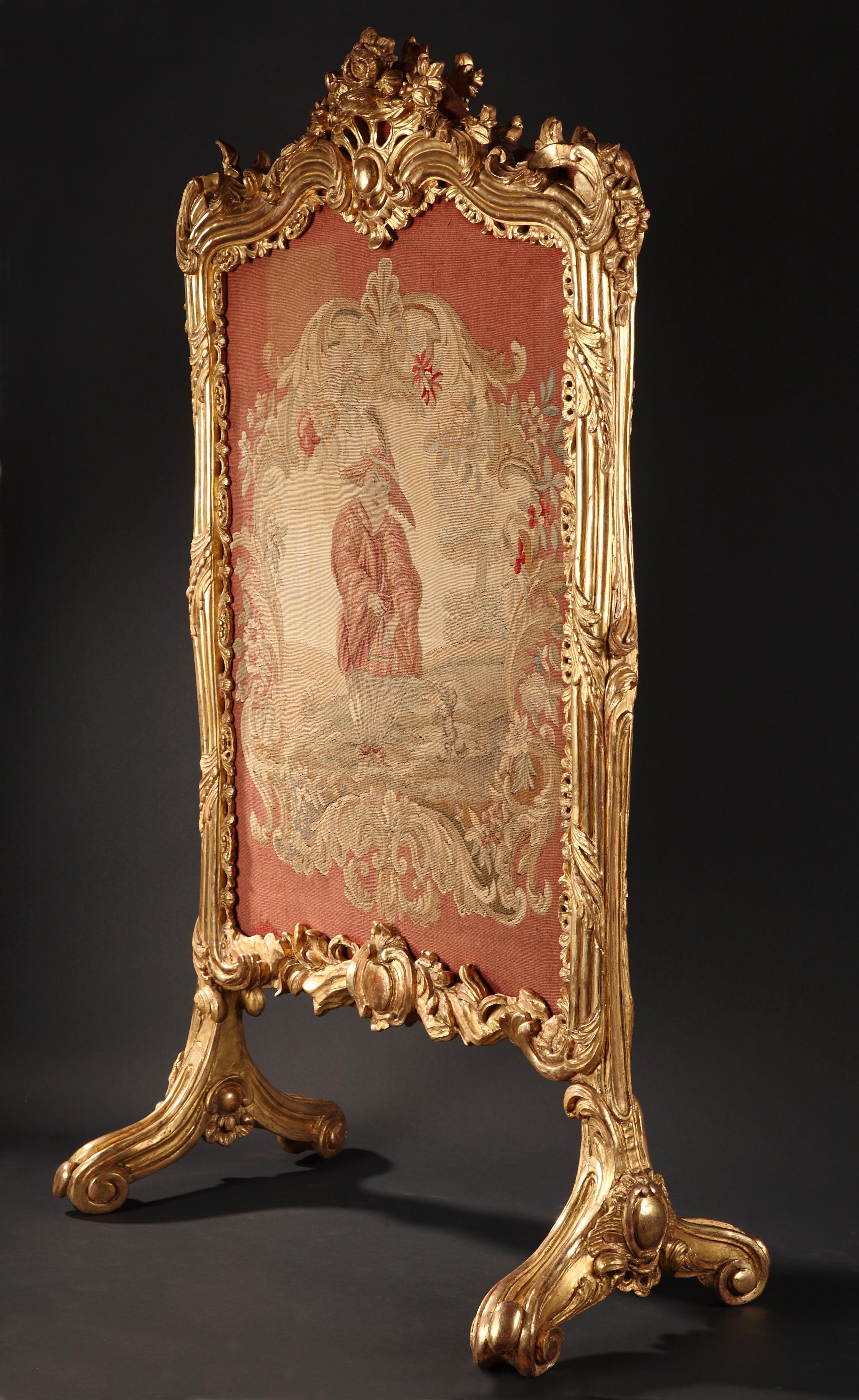 A very fine Louis XV style fire-screen beautifully carved in giltwood with acanthuses, flowers and scrolls, topped with birds, a quiver and a torch. A centred sliding panel made in Aubusson tapestry displays within a flowering frame a Chinese