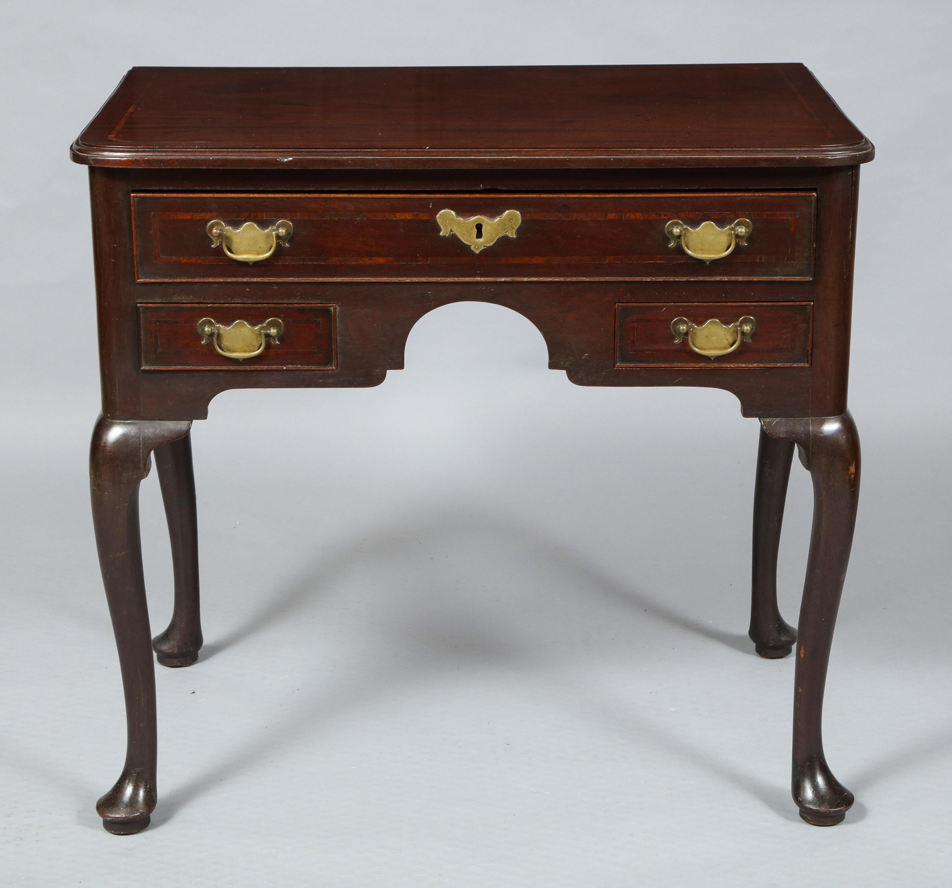 A very good Georgian mahogany Lowboy made from very dense Cuban mahogany, the shaped top with molded edge and narrow crossbanding, over on long and two short drawers with similar banding and retaining original brass hardware, standing on cabriole
