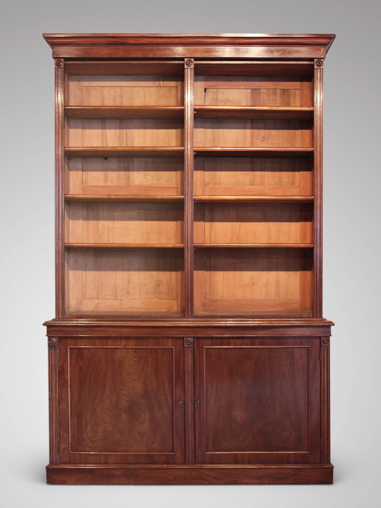 A very fine early 19th century, William IV period mahogany open library bookcase, the moulded cornice above an open bookcase with adjustable shelves, the lower section with two panelled cupboard doors, standing on an integral plinth base. England