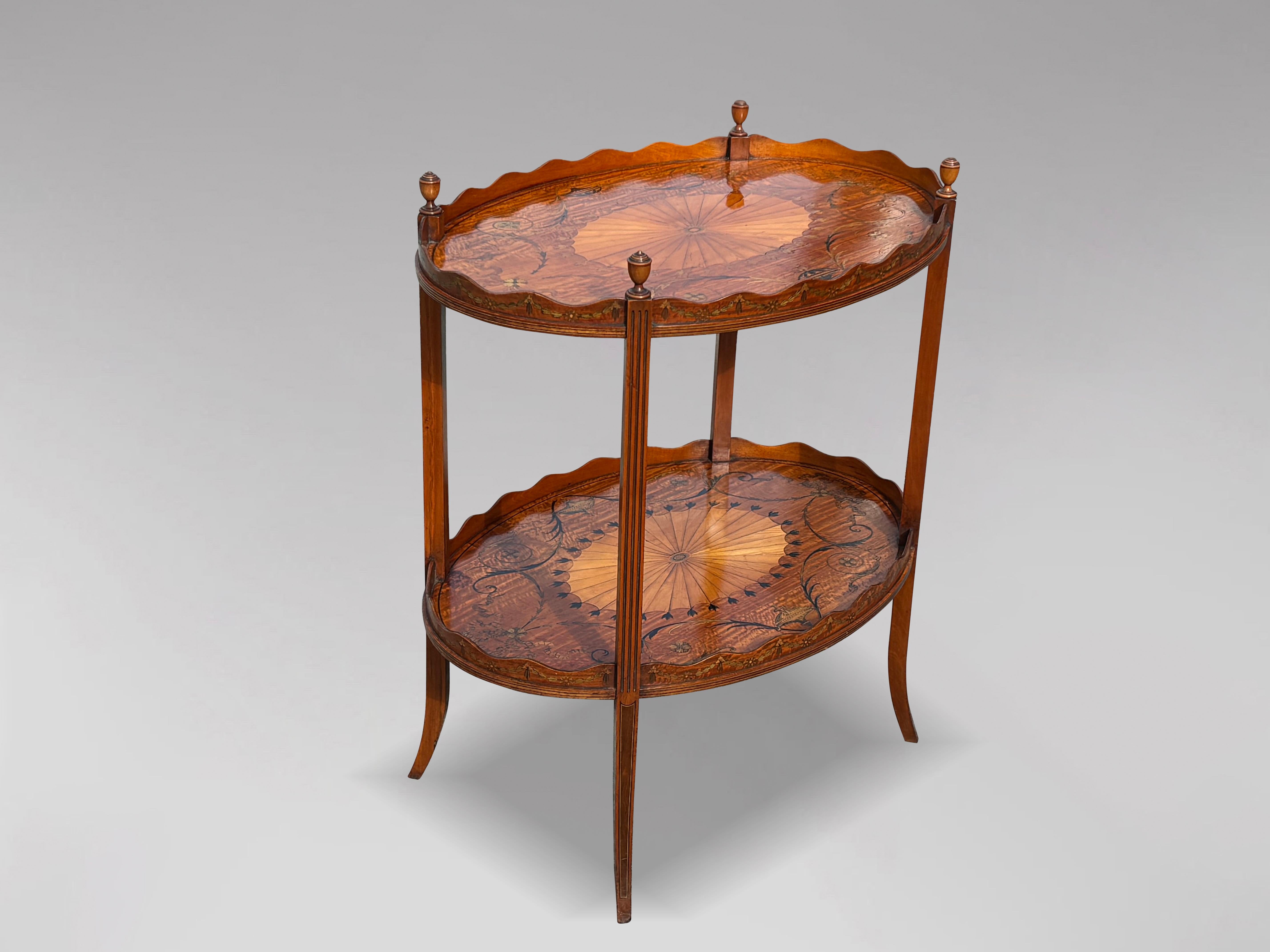 An exceptional and very fine late 19th century to early 20th century English Edwardian period mahogany and marquetry oval two-tier 'etagere' or table, in the manner of Edwards & Roberts, circa 1890. Both oval trays feature a central sunburst motif